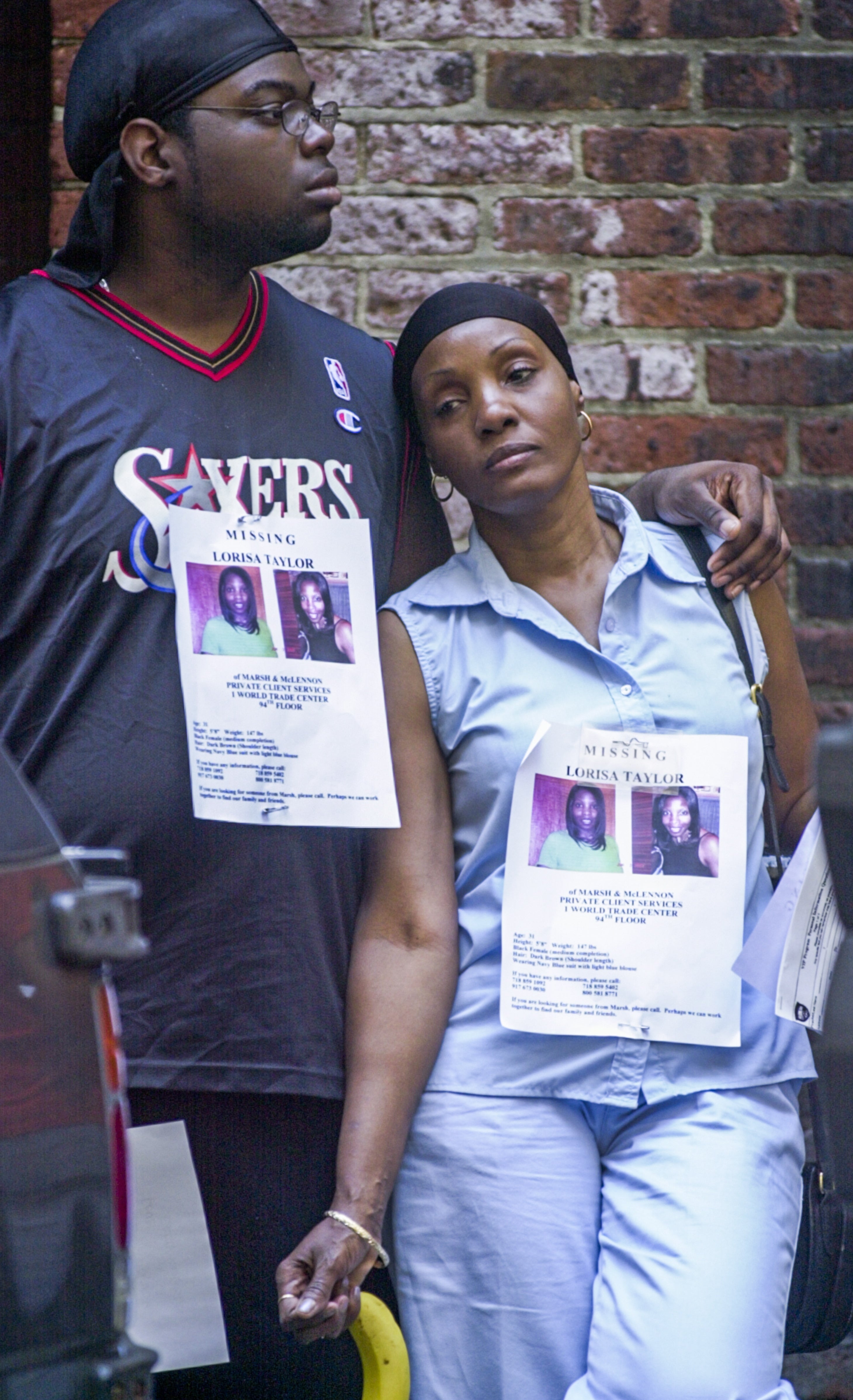 Two people wear posters of a missing woman as they seek information following the attack on the World Trade Centre