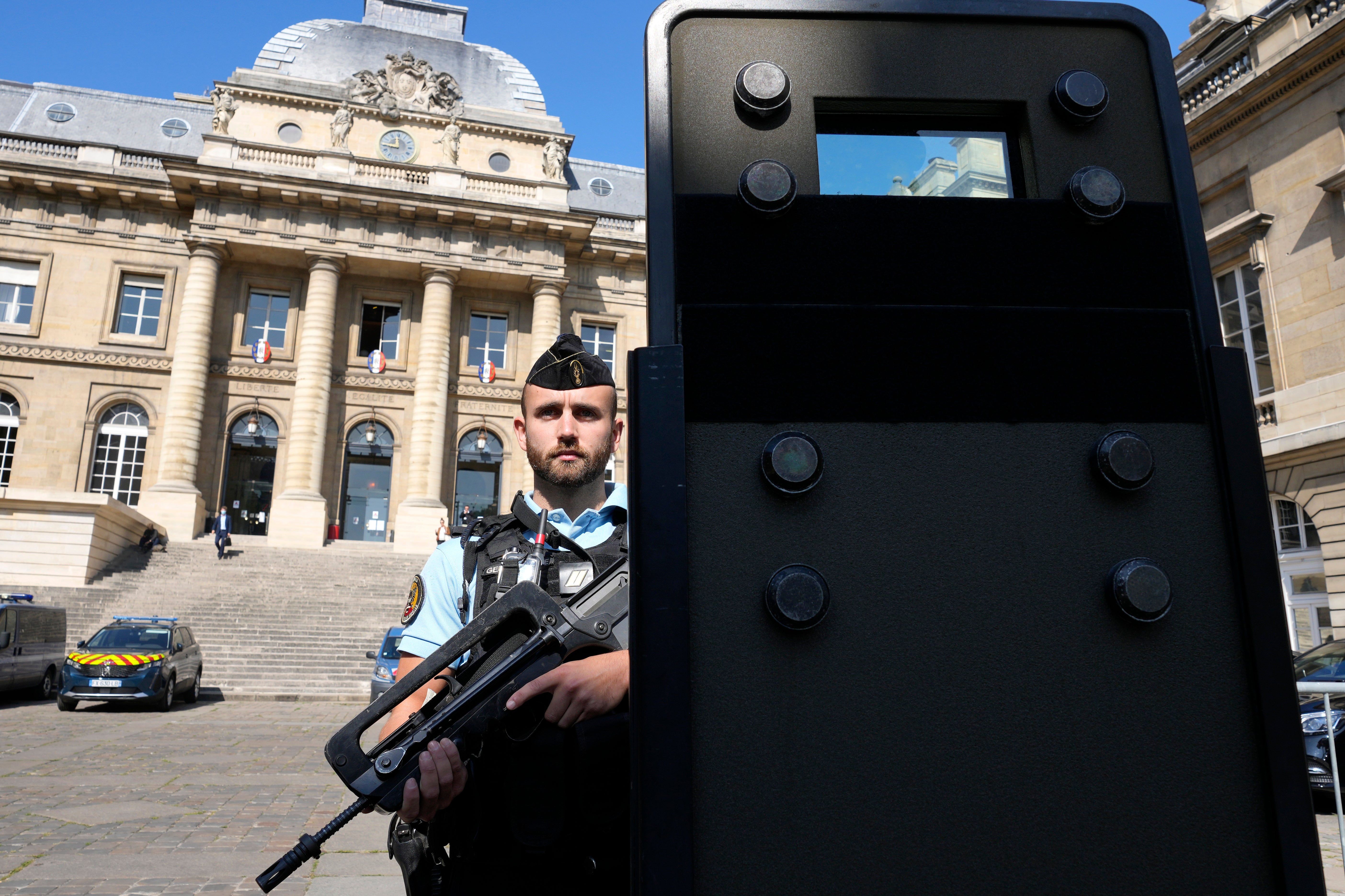A police officer stands behind a shield outside the Paris courthouse where France is putting on trial 20 men accused in the Nov 2015, Islamic State terror attacks on Paris