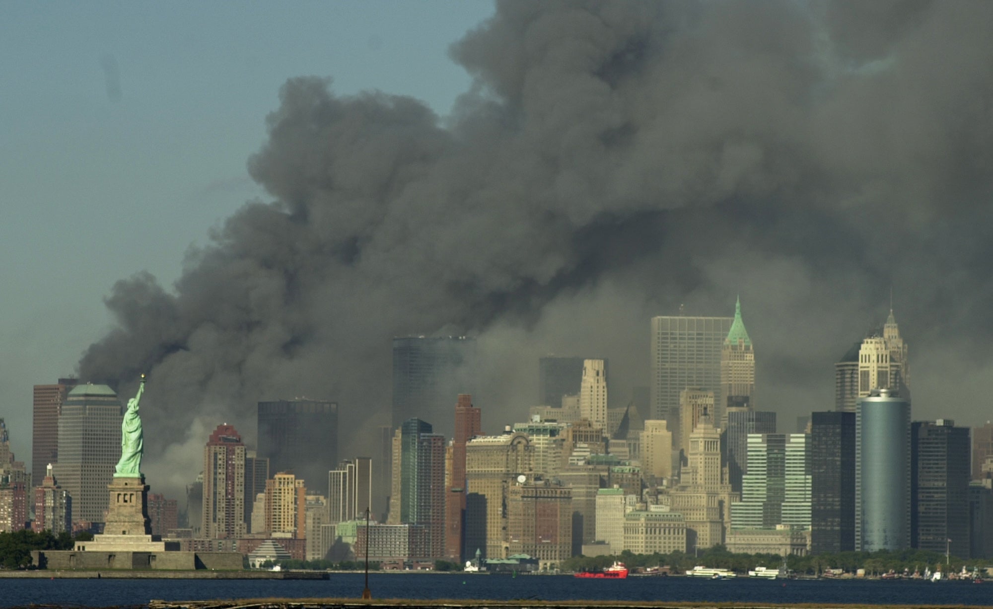 Thick smoke billows into the sky from the area behind the Statue of Liberty