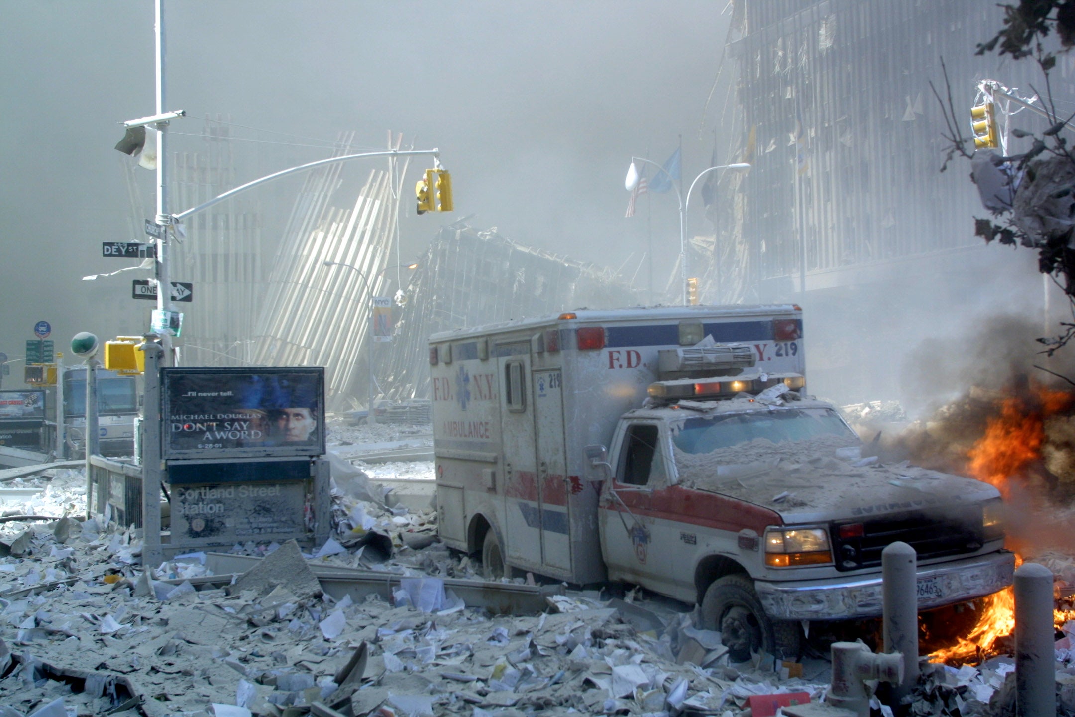 An ambulance, covered with debris and on fire, after the collapse of the first tower