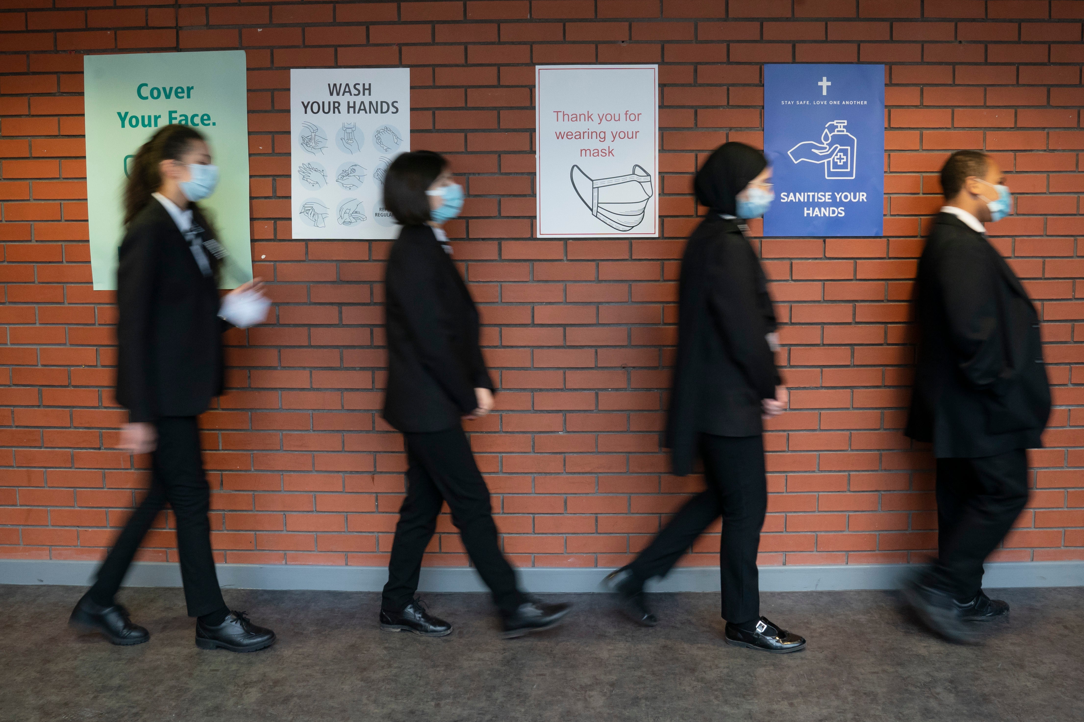 Pupils queue for a socially distanced assembly at a school in in Manchester, England