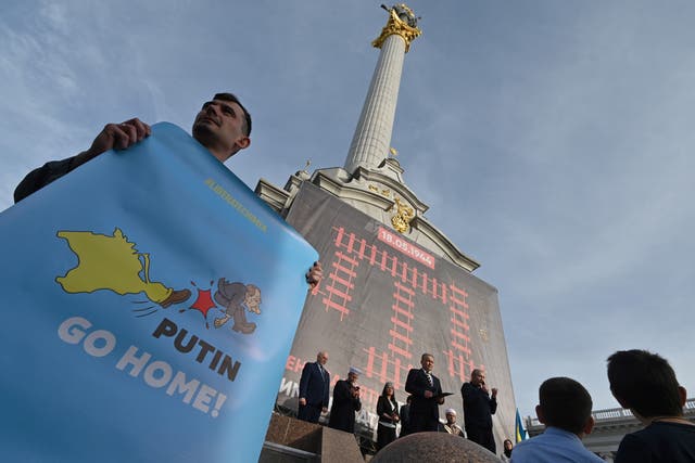 <p>A man holds and anti-Russian placard on Kyiv’s Independence Square in 2019 during a memorial for the 75th anniversary of the deportation of the Crimean population by the Soviet Union</p>