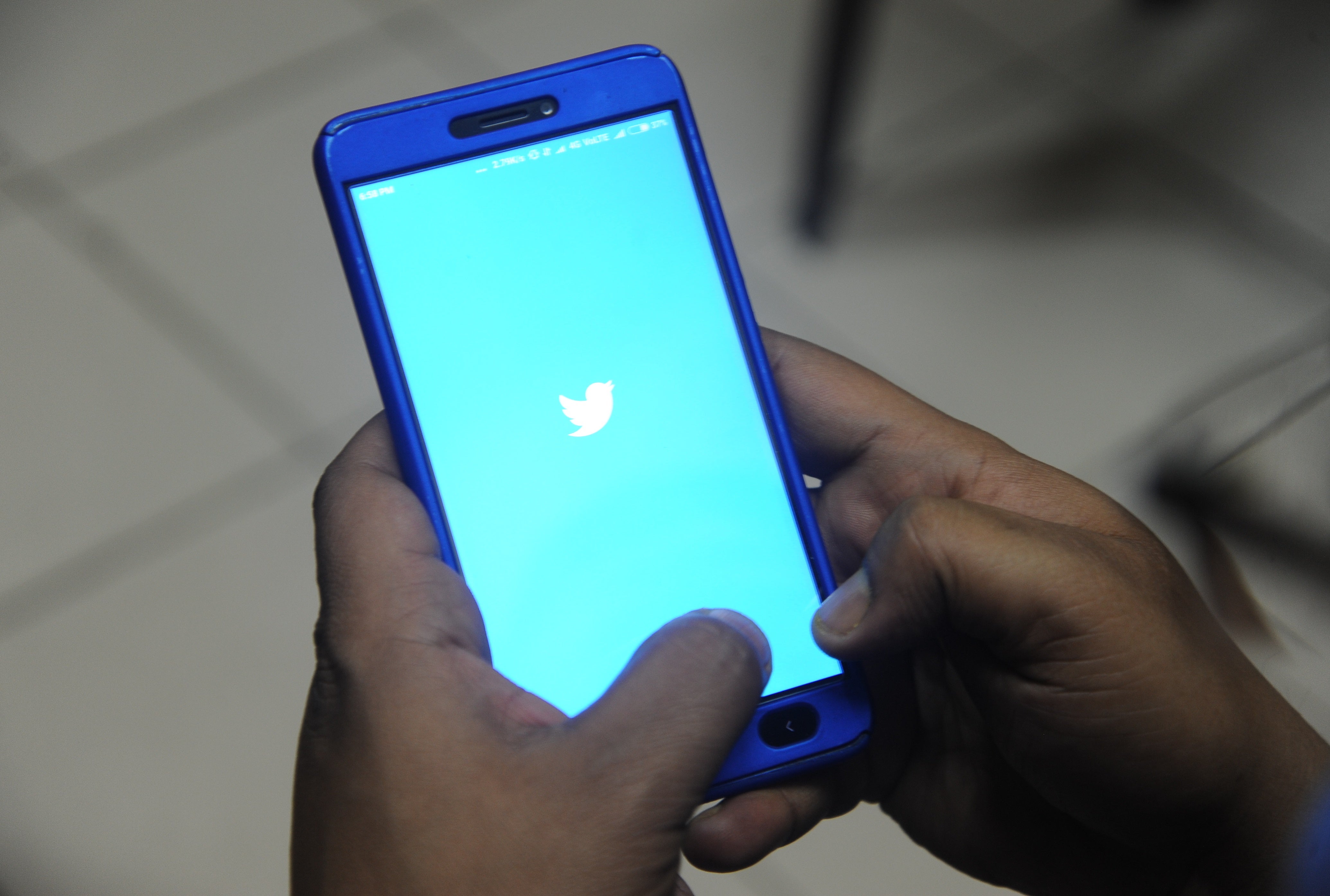 Indian man poses for a photograph using Twitter on his cellphone in Siliguri