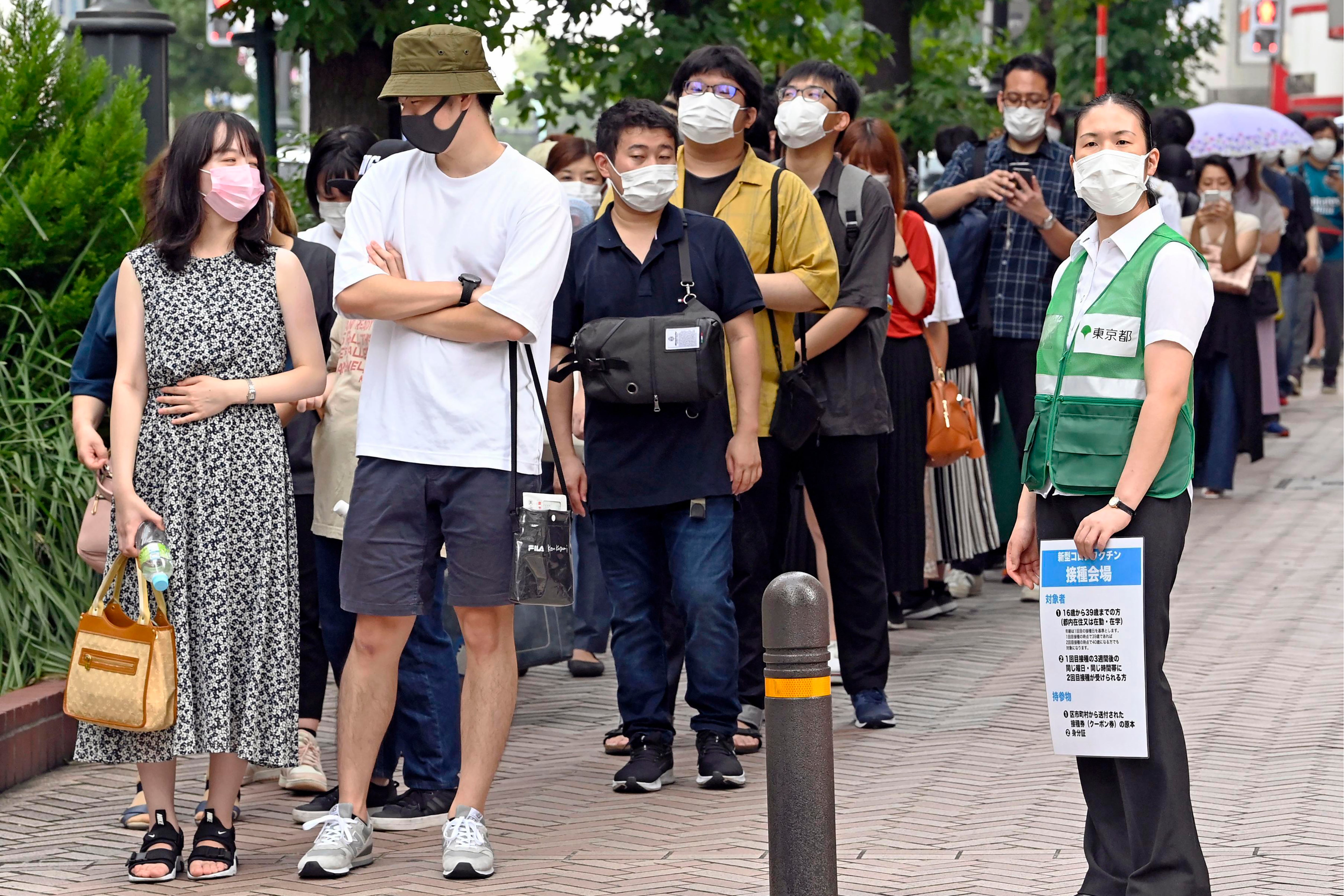 People wait in line to get lottery tickets for the coronavirus vaccine at the Shibuya district in Tokyo Saturday
