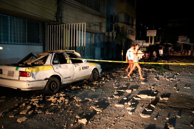 <p>Una pareja pasa junto a un taxi que resultó dañado por la caída de escombros después de un fuerte terremoto en Acapulco, Guerrero, el martes 7 de septiembre de 2021. El terremoto sacudió el sur de México cerca del complejo turístico, provocando que algunos edificios se balanceen en la Ciudad de México a 379 kilómetros de distancia.</p>