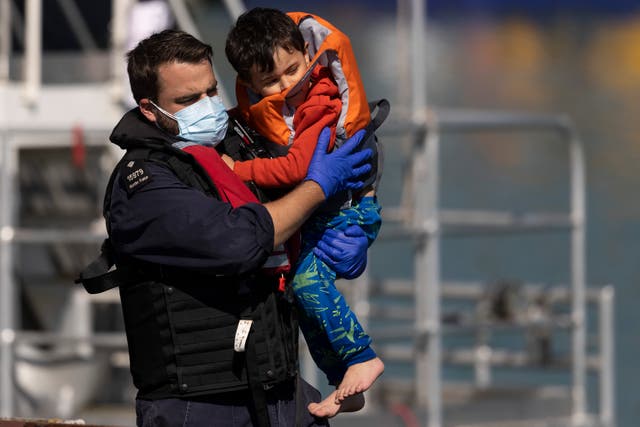 <p>A young migrant boy is carried by a Border Force official after arriving into Dover docks on 8 September </p>