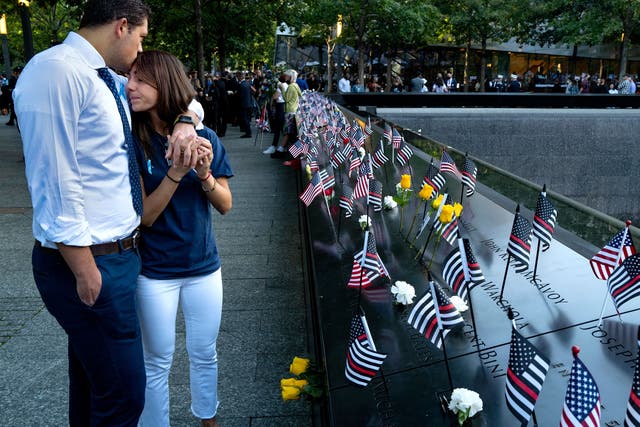 <p>Katie Mascali is comforted by her fiancé Andre Jabban as they stand near the name of her father Joseph, with FDNY Rescue 5, on Saturday </p>