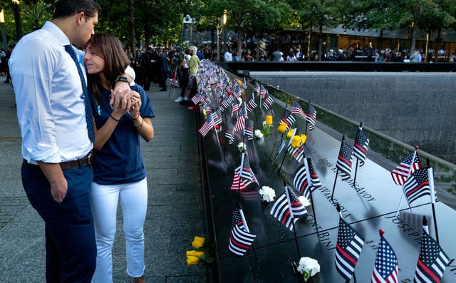 <p>Katie Mascali is comforted by her fiancé Andre Jabban as they stand near the name of her father Joseph, with FDNY Rescue 5, on Saturday </p>