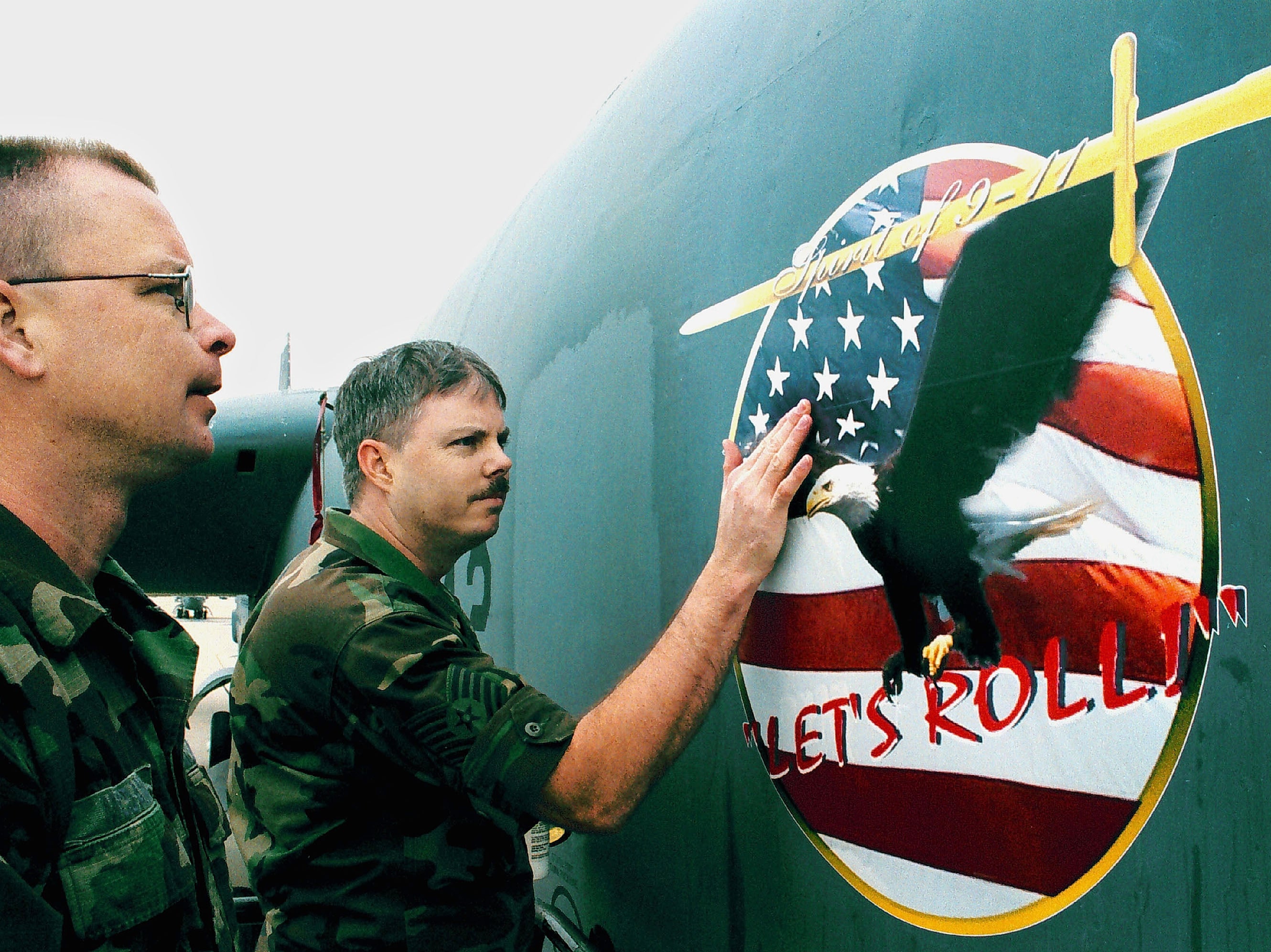 U.S. Air Force Reservists Tech. Sgt. Ron (L) and Staff Sgt. Brian of the 93rd Bomber Squadron apply a decal with the phrase "Lets Roll" to the side of a B-52 bomber February 20, 2002