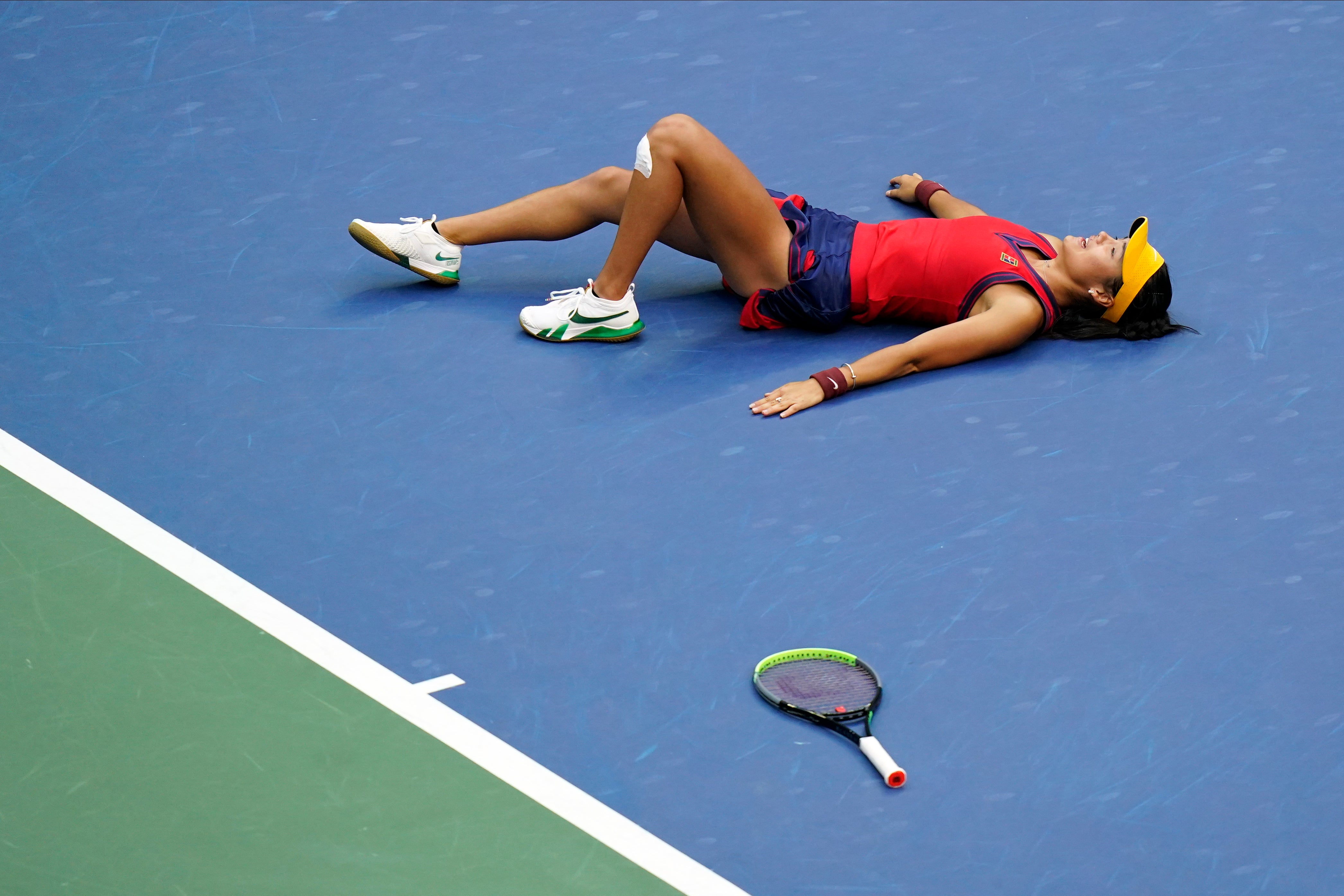 Emma Raducanu lies on the court after beating Leylah Fernandez (Frank Franklin II/AP)