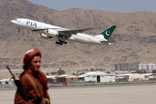 <p>A Taliban fighter stands guard as a Pakistan International Airlines plane, the first commercial international flight to land since the Taliban retook power last month, takes off on 13 September 2021</p>