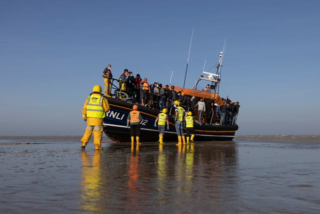 Esta foto de la semana pasada muestra a un grupo de solicitantes de asilo que llegan a la playa de Dungeness en un barco de la RNLI.