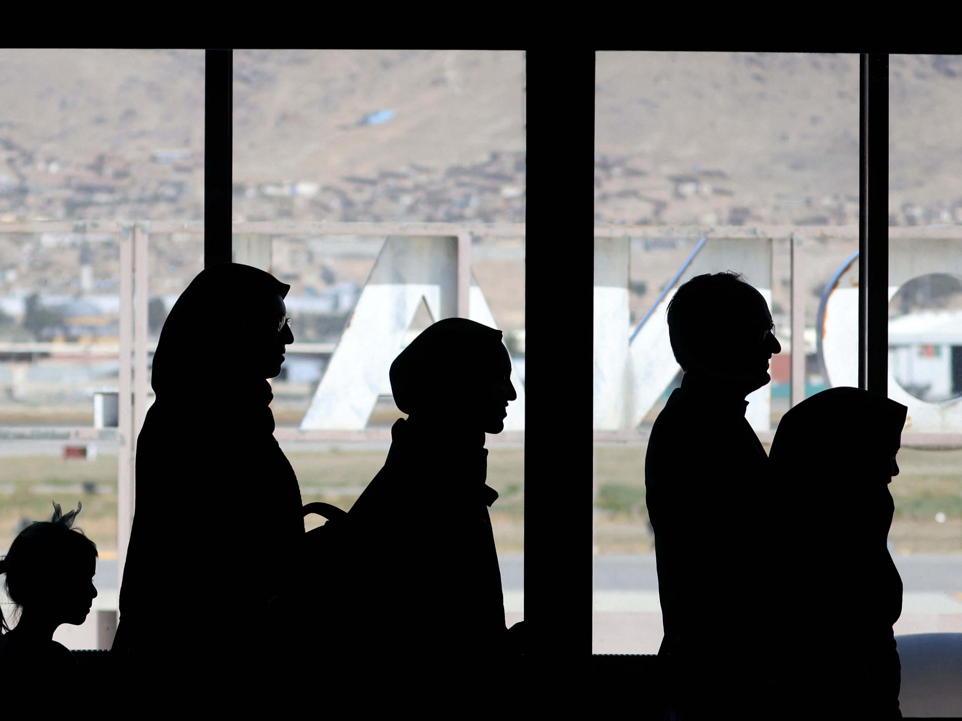 People wait to board a flight permitted to leave Kabul airport on 13 September
