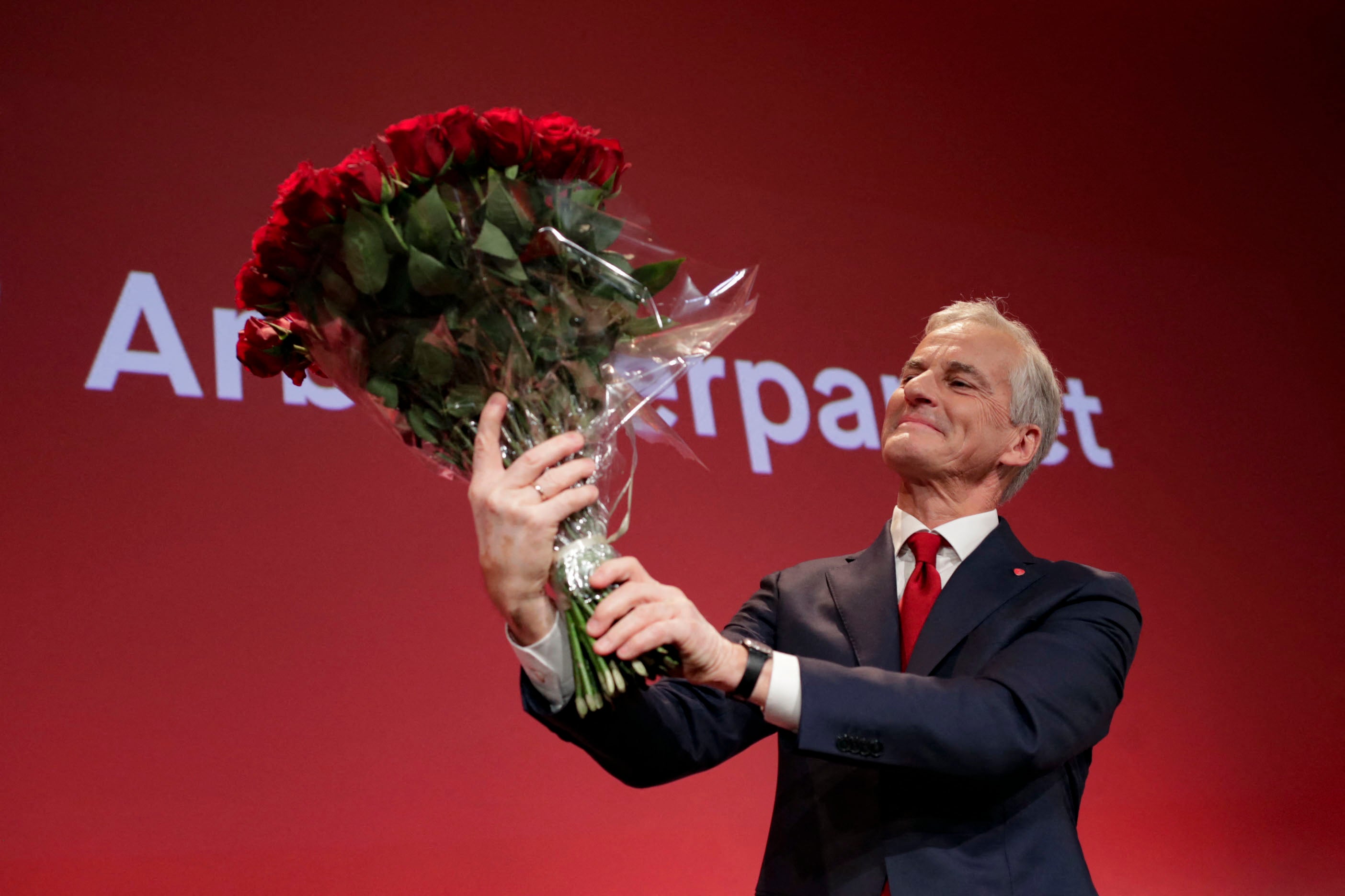 Labour leader Jonas Gahr Store holds a bouquet of red roses after the results of the election