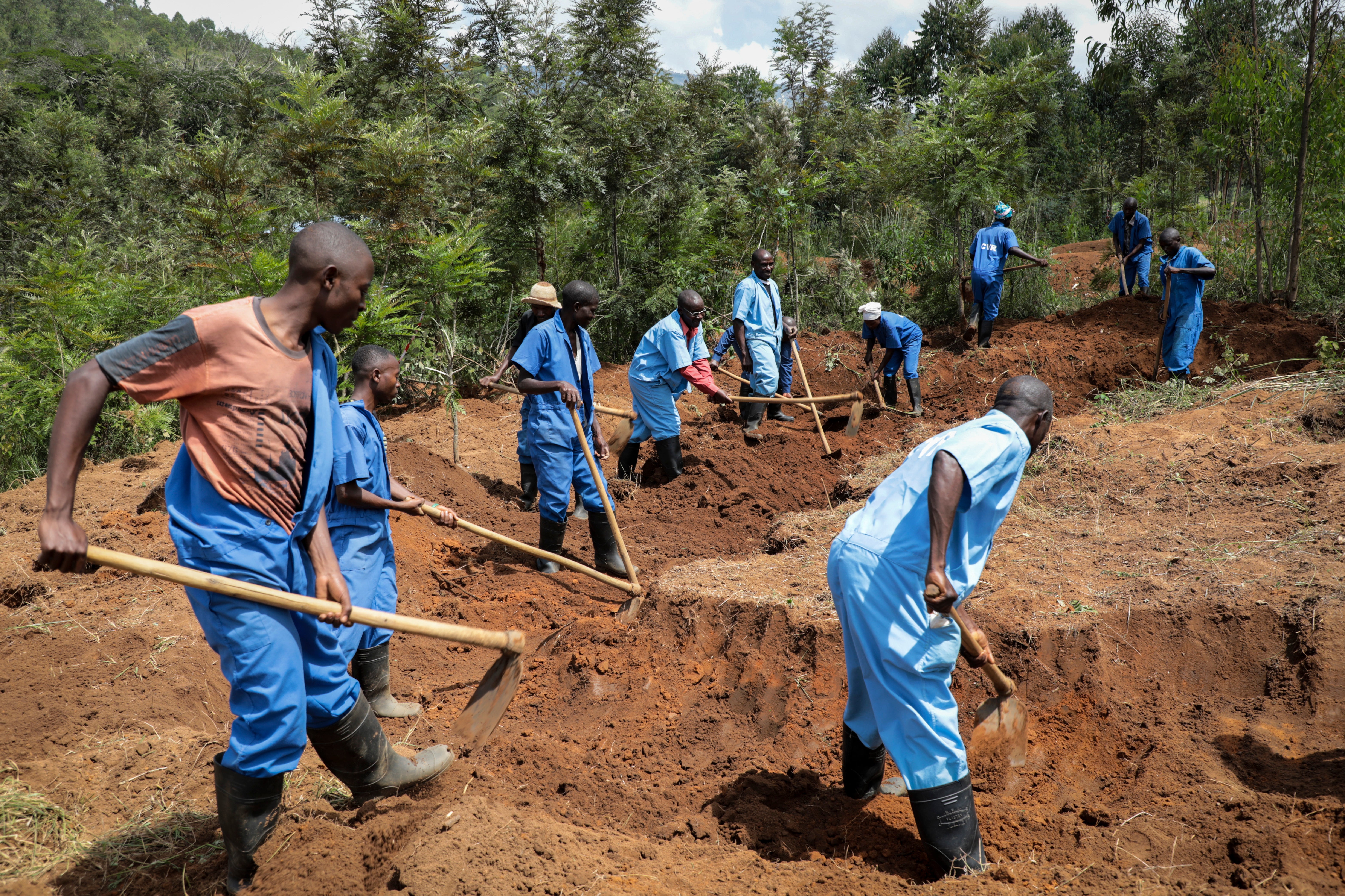 Truth and reconciliation commission workers dig for human remains at the site of a mass grave on Bukirasazi hill in February 2020