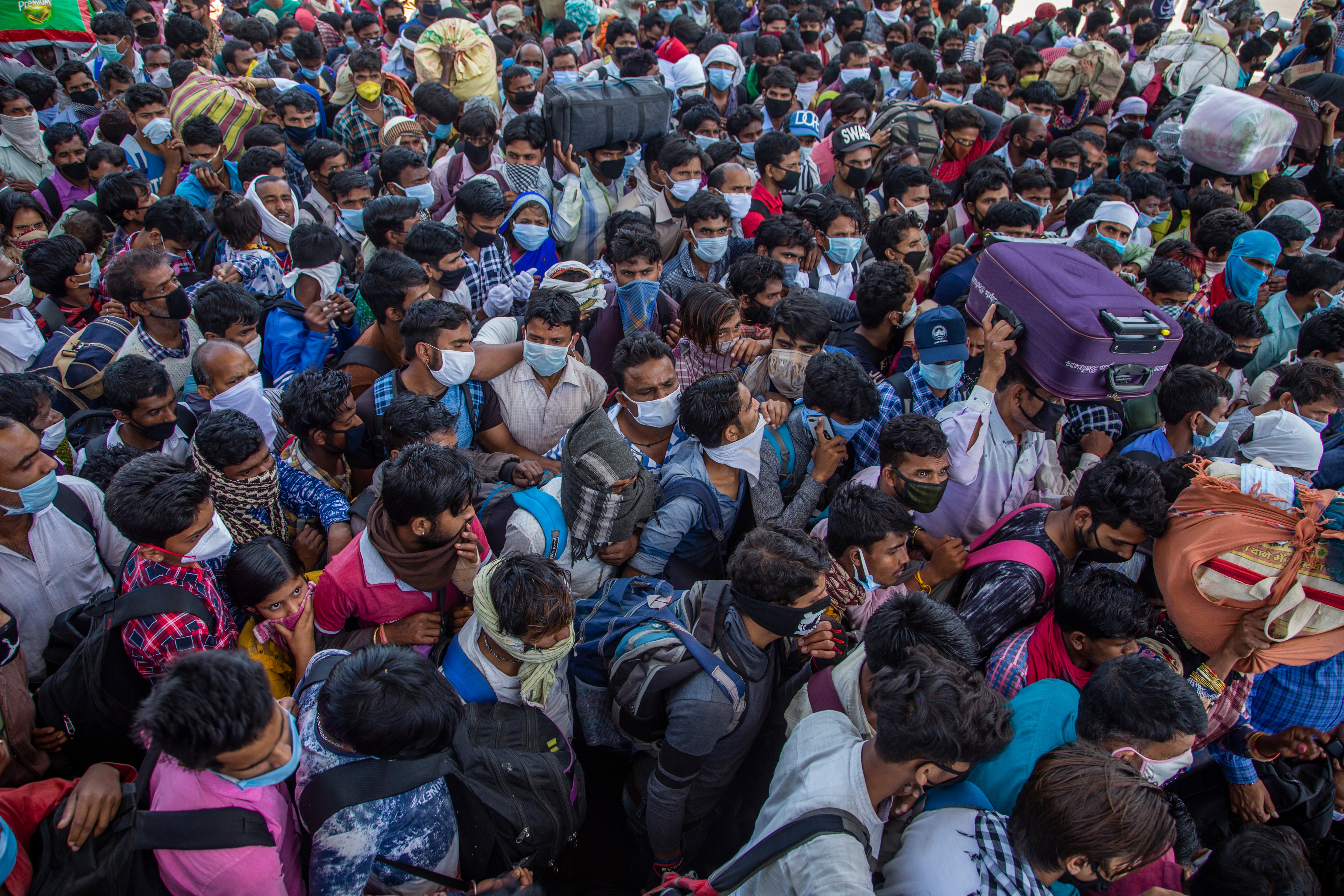 Indian migrant workers and labourers along with their families board buses to return to their native villages during the lockdown in March 2020