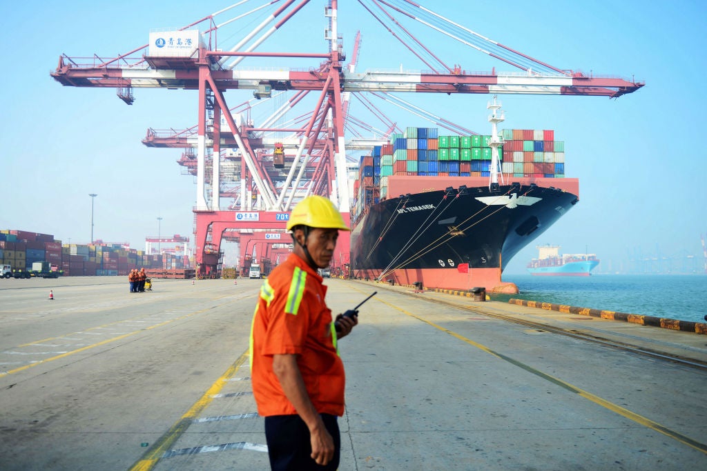 A Chinese worker looks on as a cargo ship is loaded at a port in Qingdao, eastern China's Shandong province on 13 July 2017.