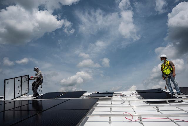 <p>Employees with Ipsun Solar install solar panels on the roof of the Peace Lutheran Church in Alexandria, Virginia on May 17, 2021. </p>