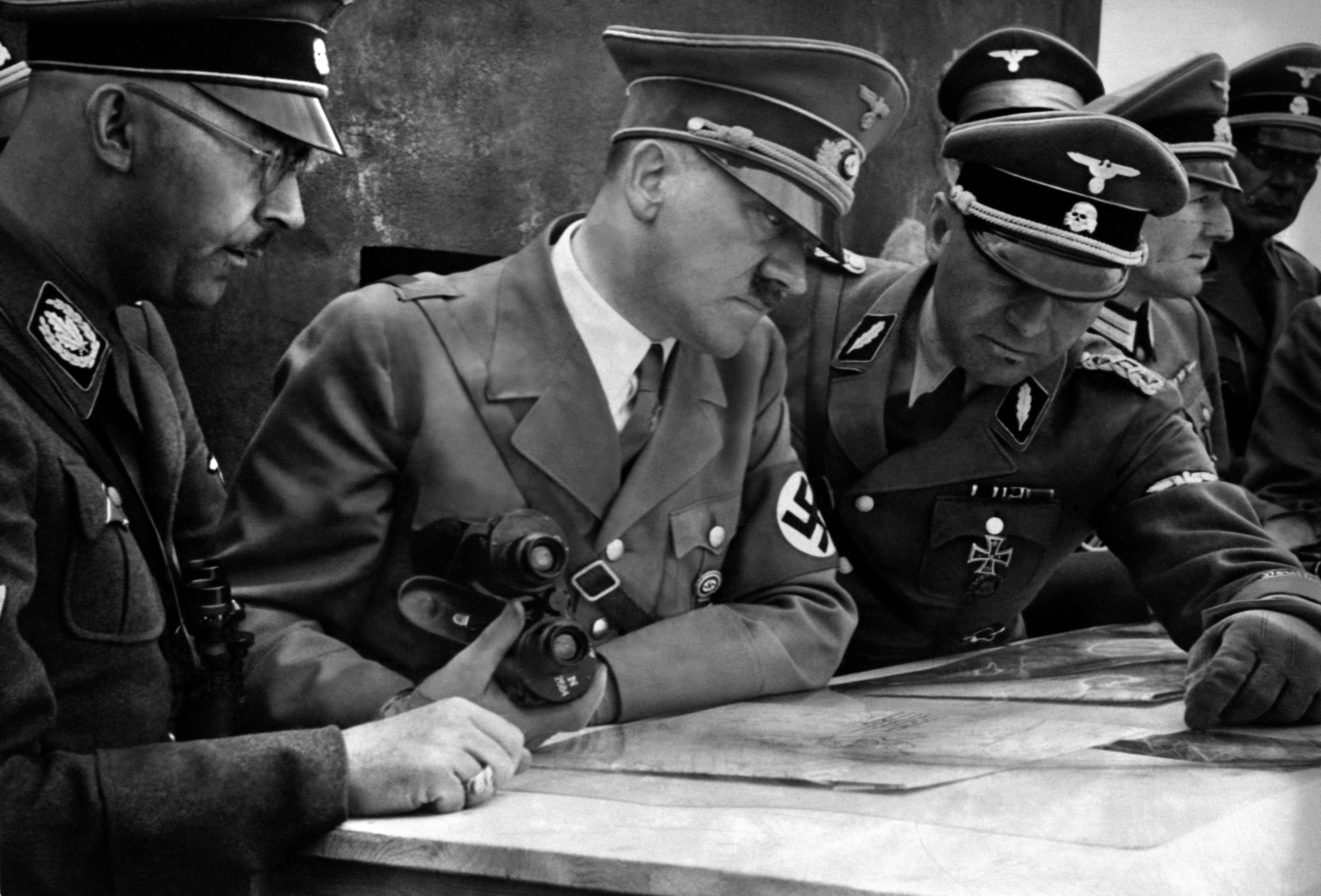 <p>A picture dated 1939 shows German Nazi Chancellor and dictator Adolf Hitler (C) consulting a geographical survey map with his general staff including Heinrich Himmler (L) and Martin Bormann (R) at an unlocated place during World War II</p>