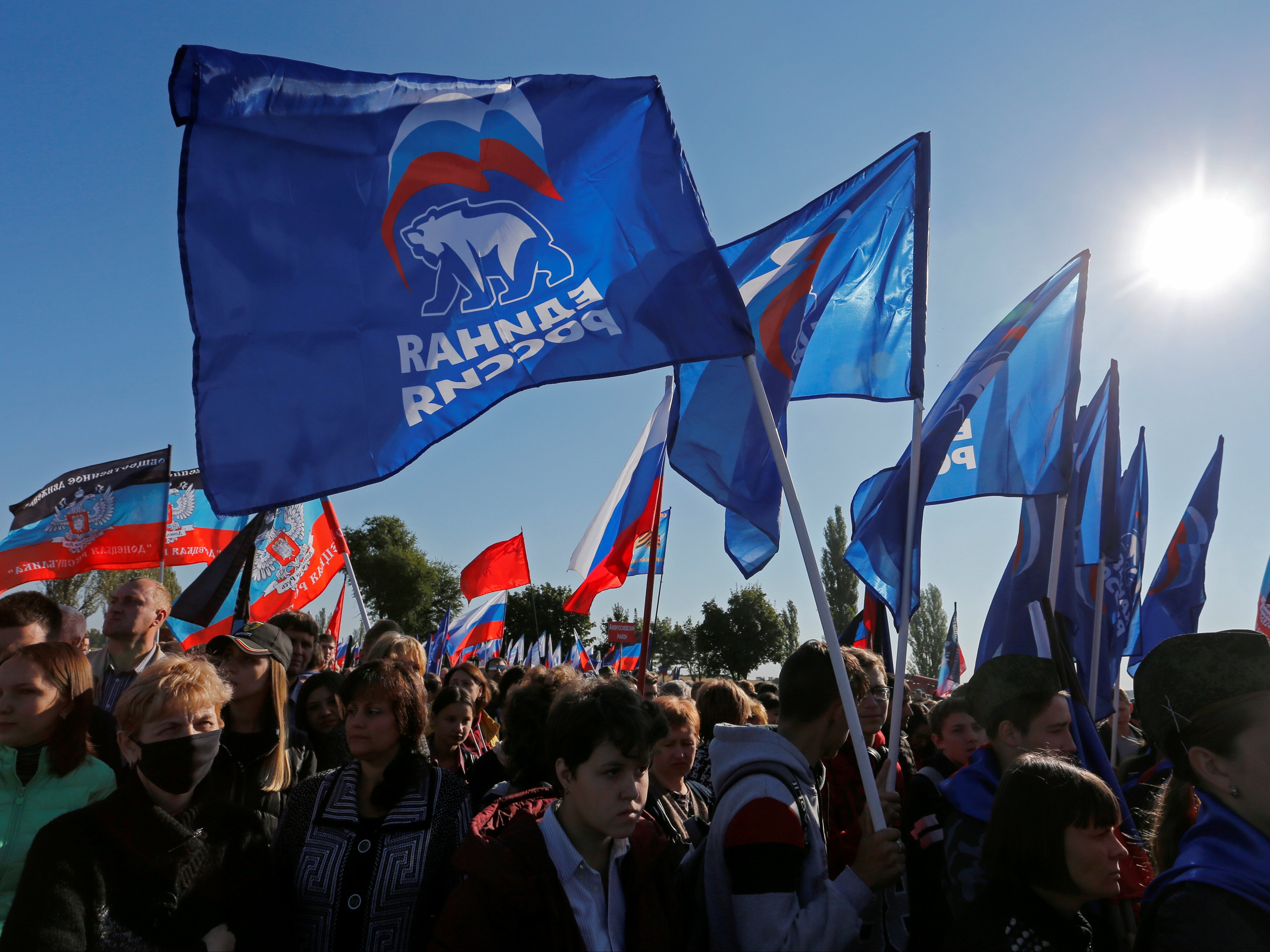 People hold flags of Russia’s ruling United Russia party, during a rally at the war memorial complex Savur-Mohyla