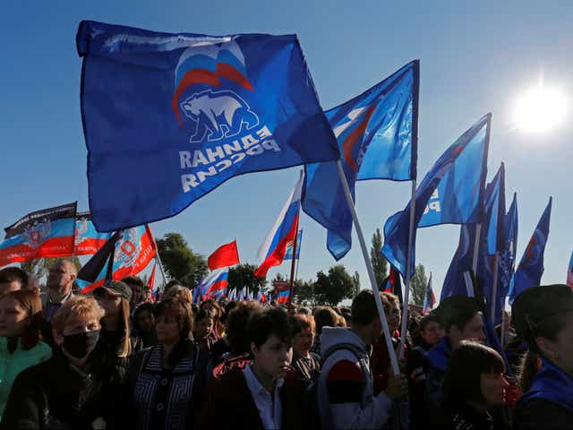 <p>People hold flags of Russia’s ruling United Russia party, during a rally at the war memorial complex Savur-Mohyla</p>