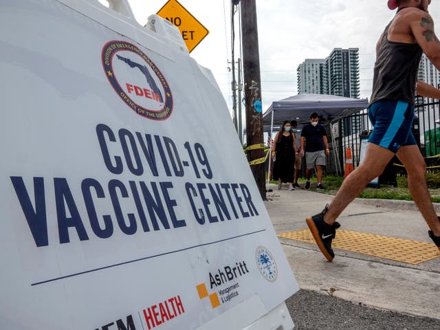 <p>A man walks by a Covid vaccination centre in Florida </p>