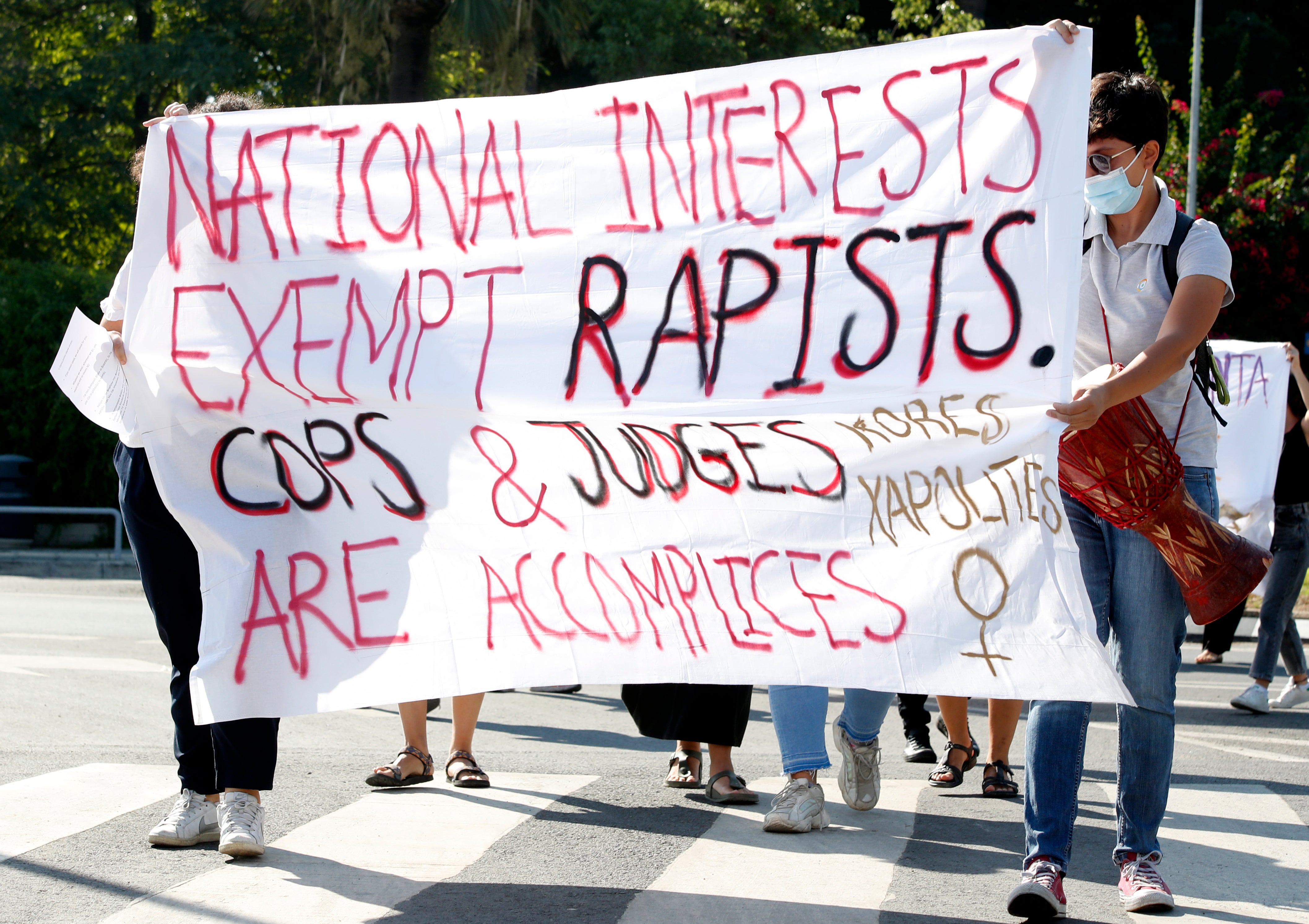 Protesters hold a banner in support of a British woman who appealed her conviction for making false claims that she was gang raped at a resort on the island in 2019