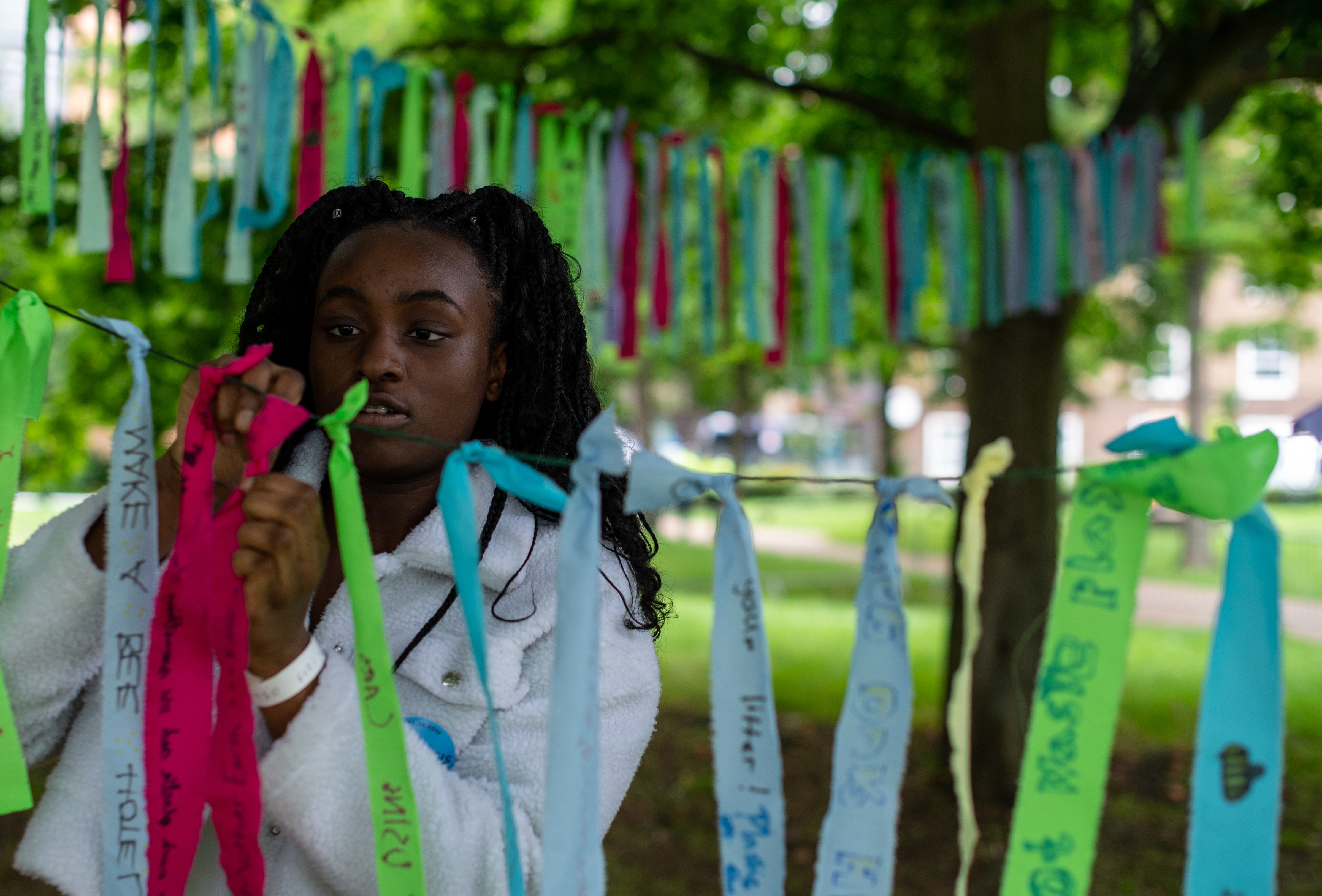 A school child writes what she loves about the natural world and what she wants to protect on cloth ribbons at the biggest ever lobby of Parliament on climate and nature