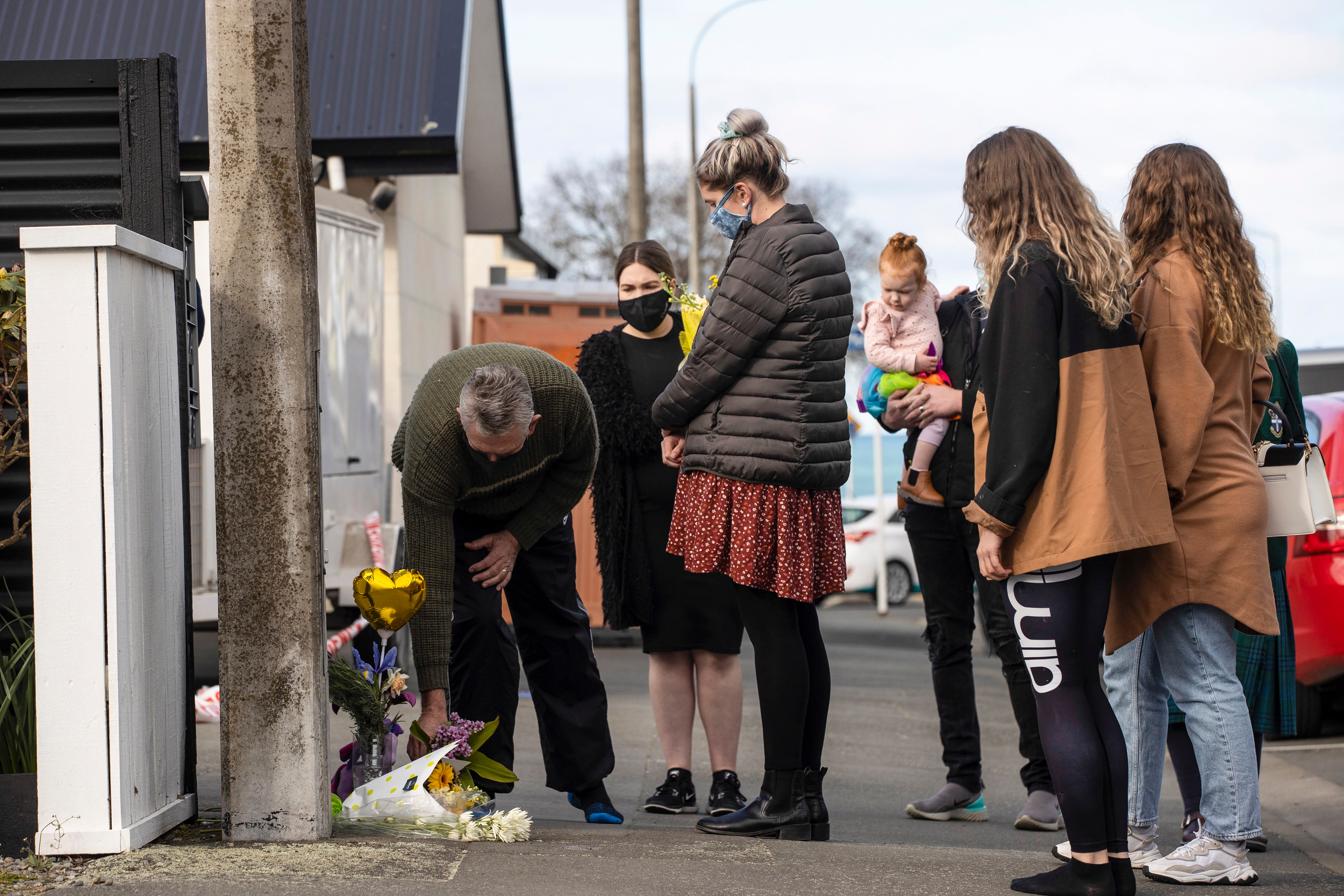 People lay flowers outside of a house where three children were found dead