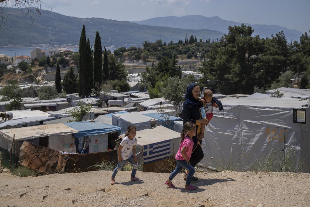 An Afghan woman with her three children walk outside the perimeter of the refugee camp at the port of Vathy on the eastern Aegean island of Samos, Greece, on Friday, 11 June