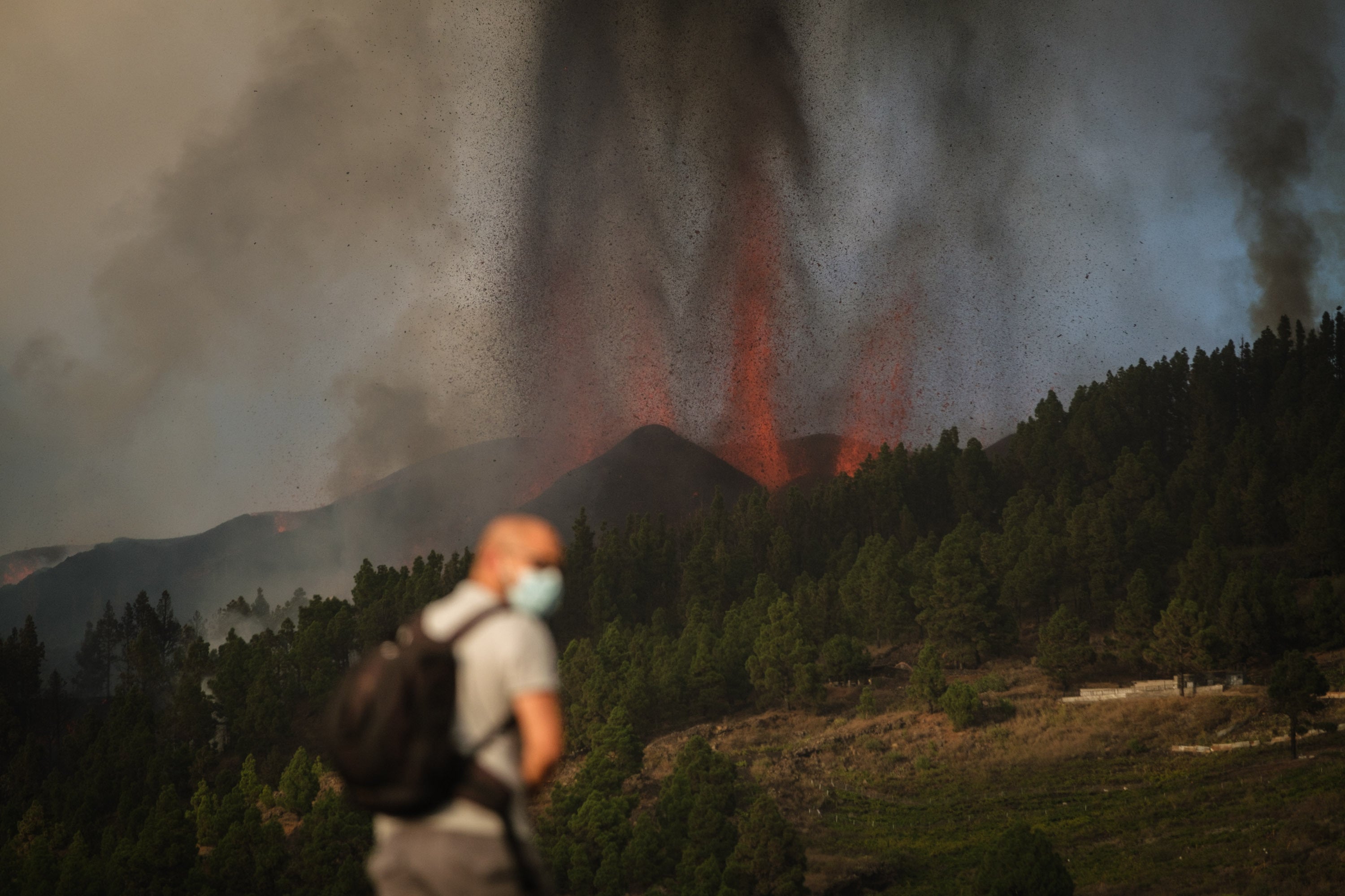A masked man watches on as lava spews from the volcano on La Palma island