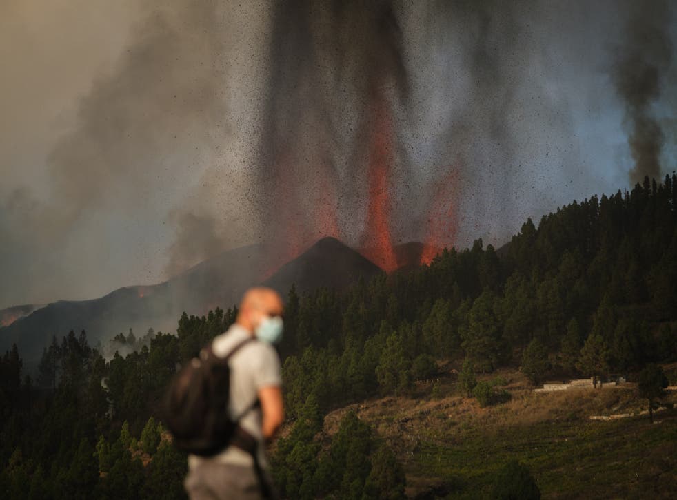 pA masked man watches on as lava spews from the volcano/p