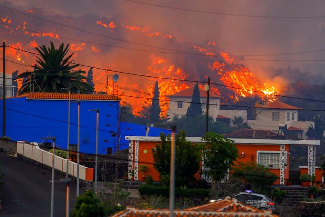 <p>Lava flows behind houses following the eruption of a volcano in La Palma</p>