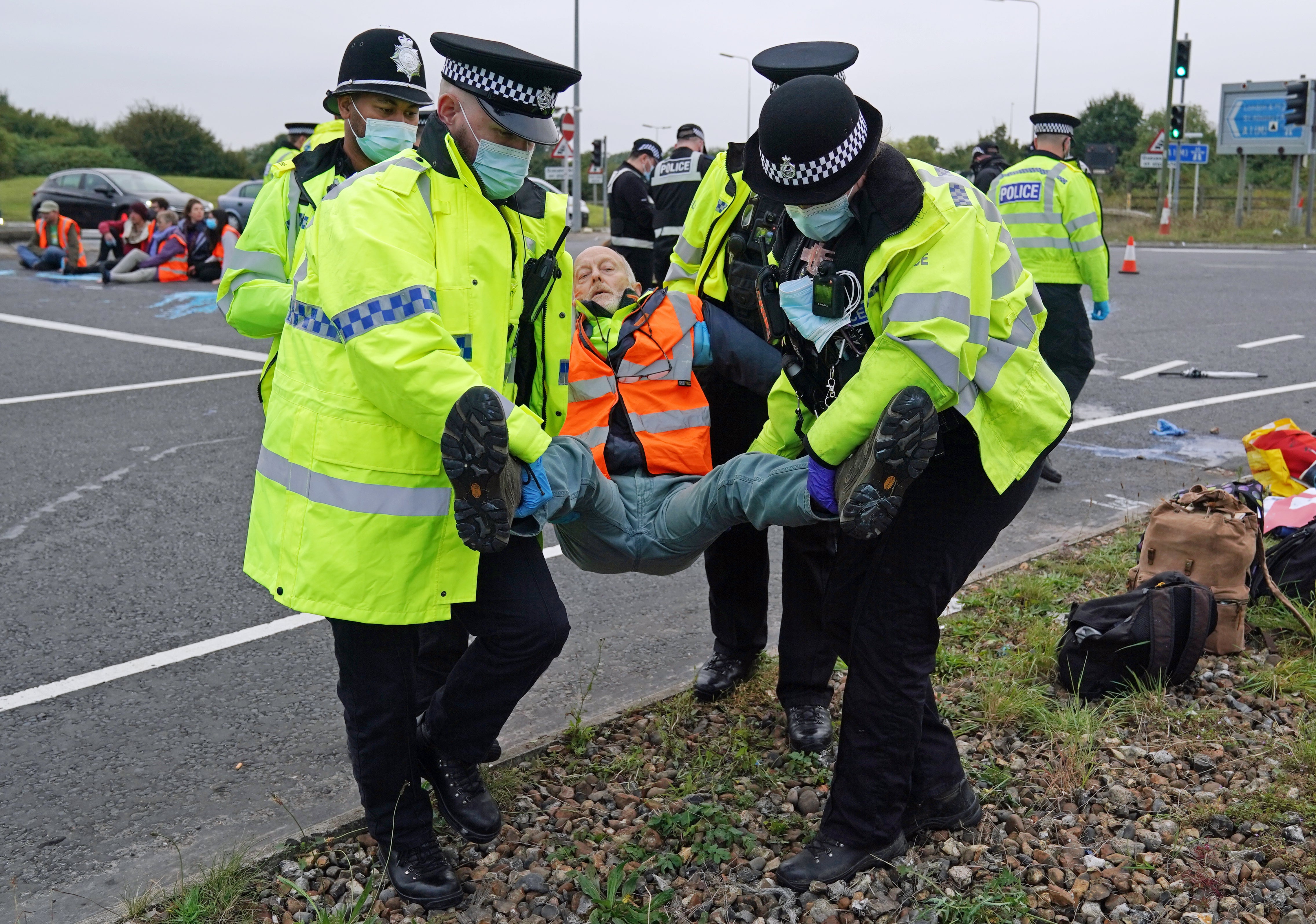 Police officers carry away an Insulate Britain protester who had glued himself to the highway at a slip road at Junction 4 of the A1(M), near Hatfield