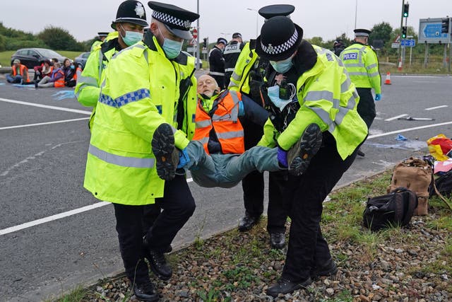 <p>Police officers carry away an Insulate Britain  protester who had glued himself to the highway at a slip road at Junction 4 of the A1(M), near Hatfield</p>