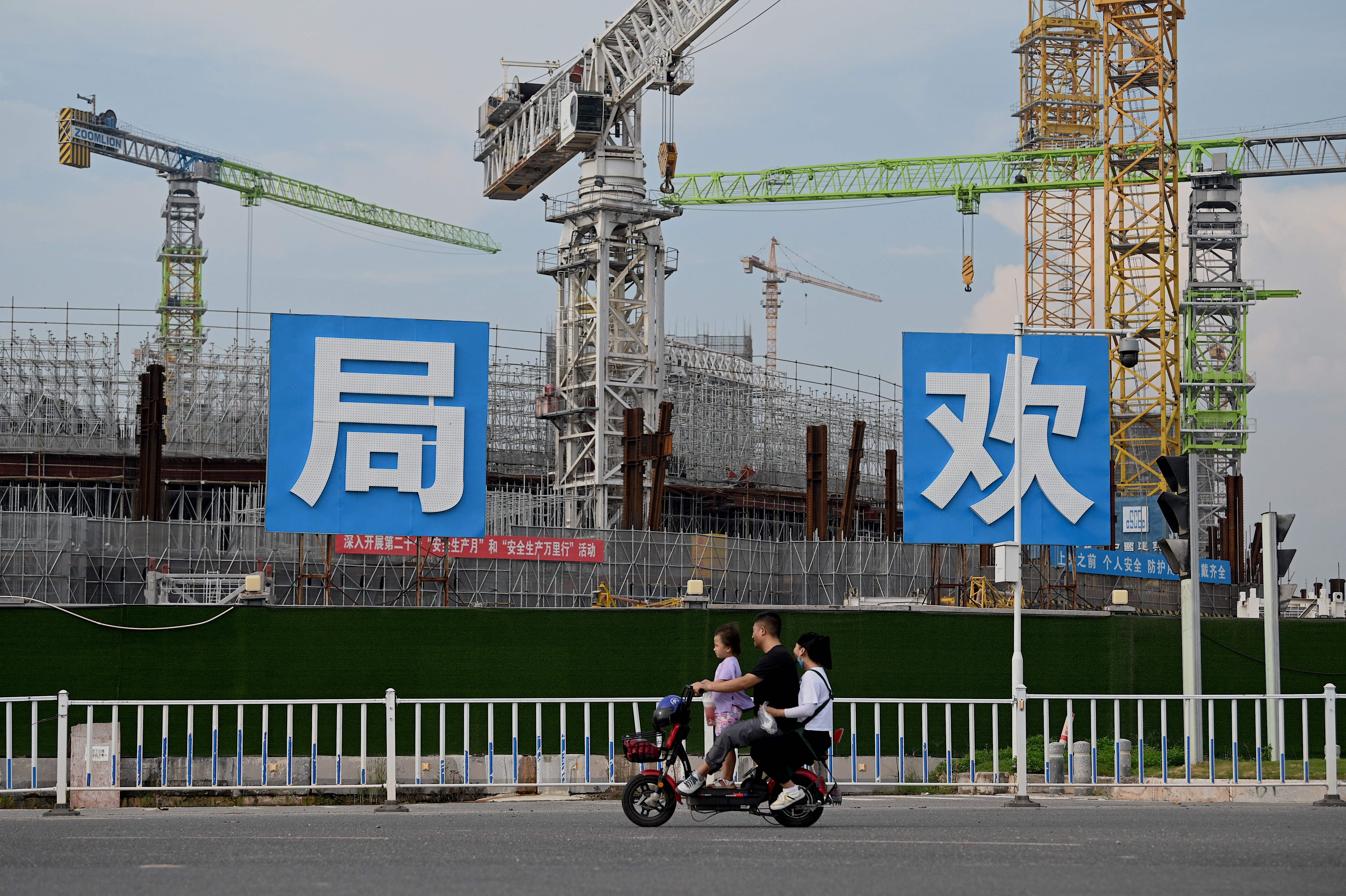 People commute in front of the under-construction Guangzhou Evergrande football stadium in Guangzhou, China’s southern Guangdong province