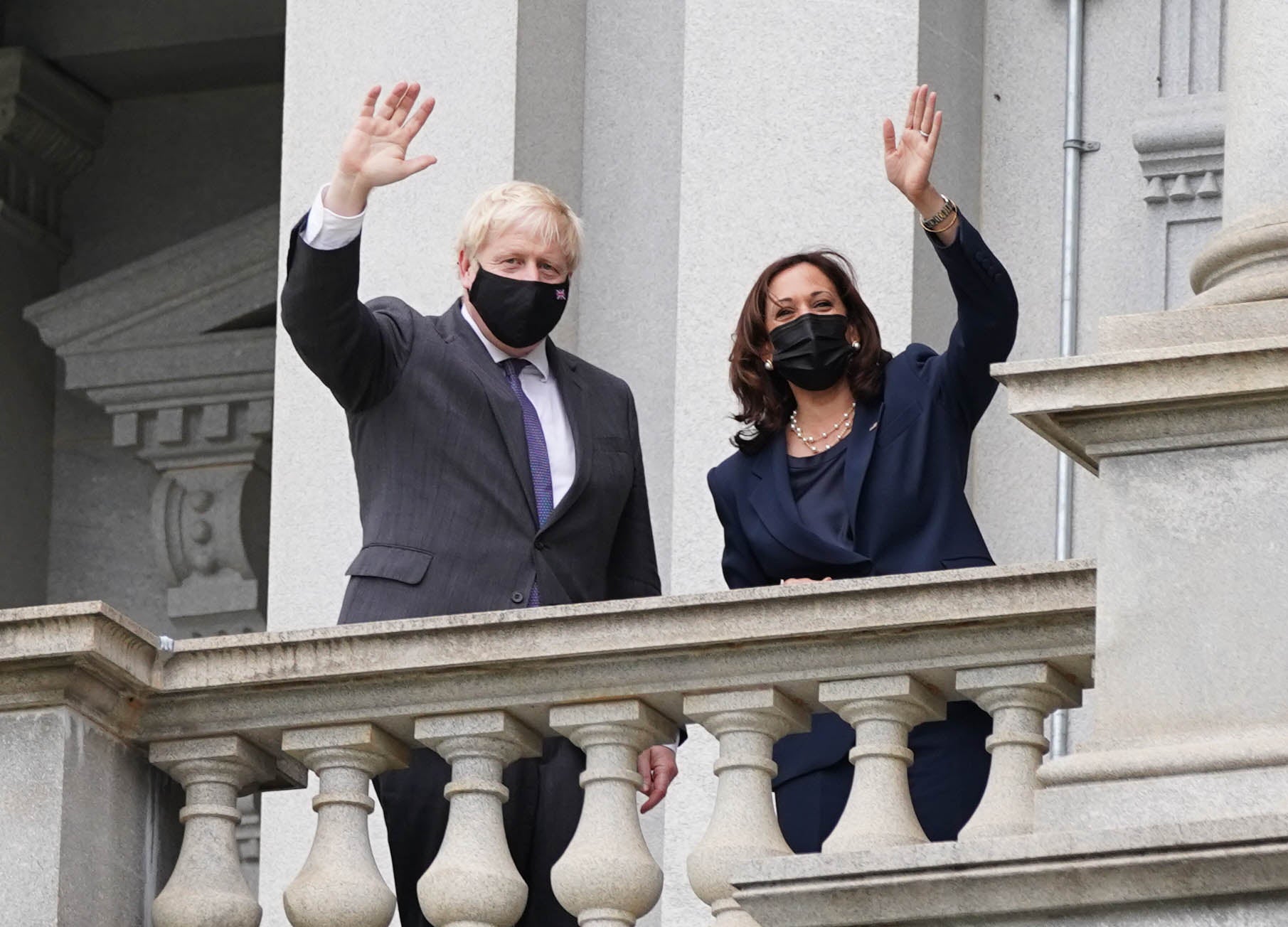 Boris Johnson and vice president Kamala Harris wave from a balcony of the Eisenhower Executive Office Building (Stefan Rousseau/PA)