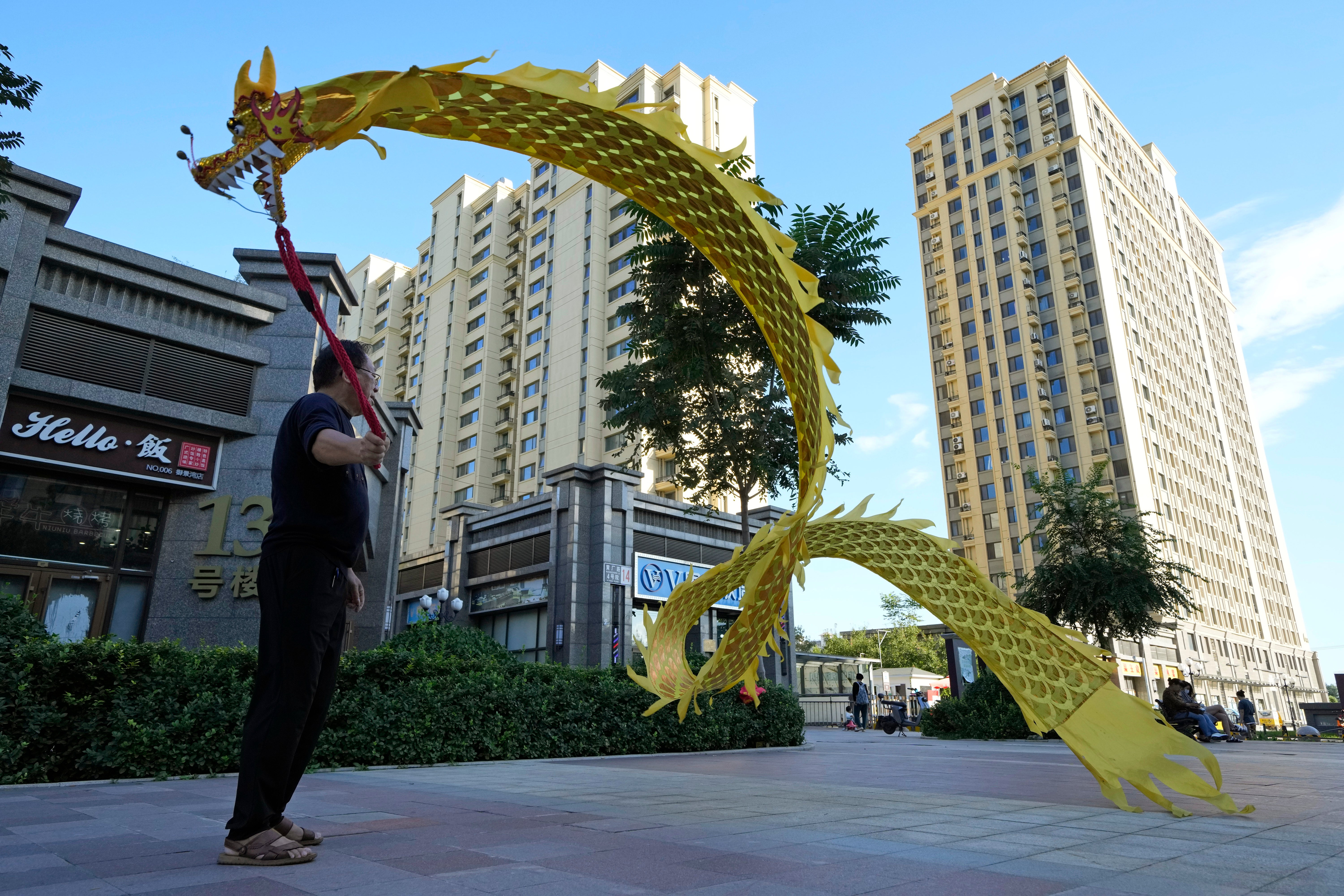 A resident wields a cloth dragon outside the Evergrande Yujing Bay residential complex in Beijing, China