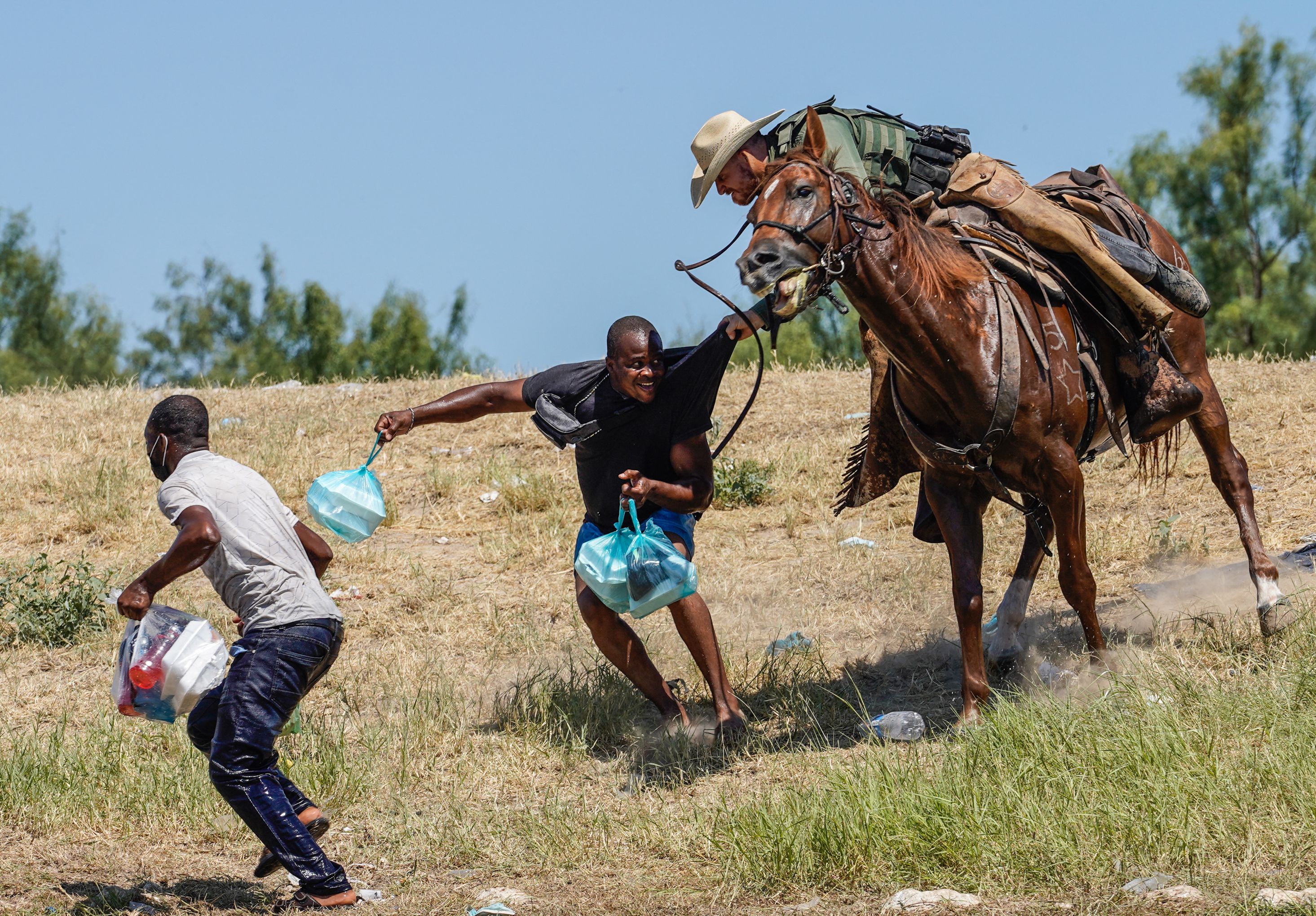 A United States Border Patrol agent on horseback tries to stop a Haitian migrant from entering an encampment on the banks of the Rio Grande near the Acuna Del Rio International Bridge in Del Rio, Texas on 19 September 2021