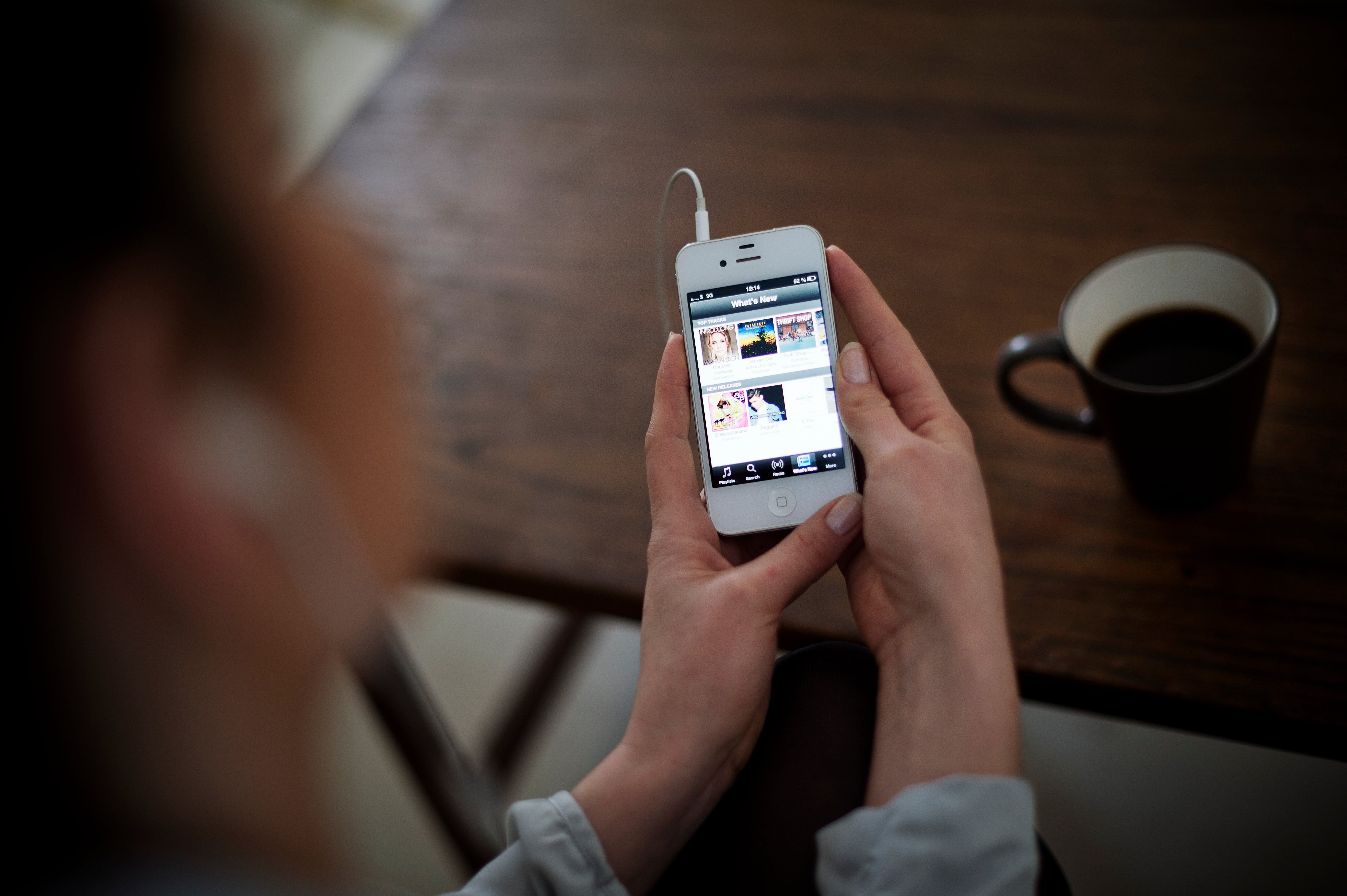 Photo shows woman using iPhone application of Swedish music streaming service Spotify