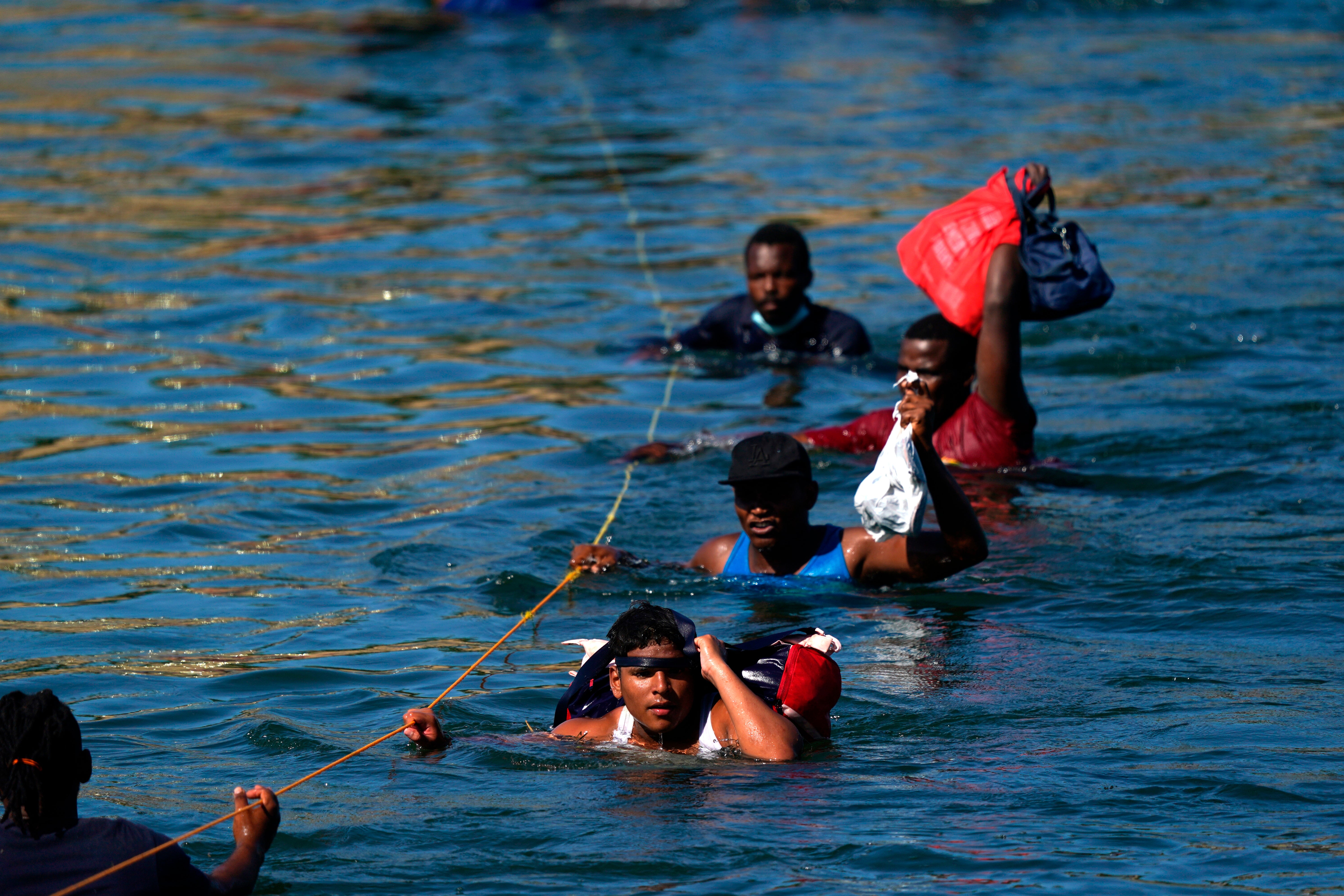 Migrants, many from Haiti, wade across the Rio Grande from Del Rio, Texas, to return to Ciudad Acuna, Mexico, Tuesday, 21 September 2021, to avoid deportation from the US