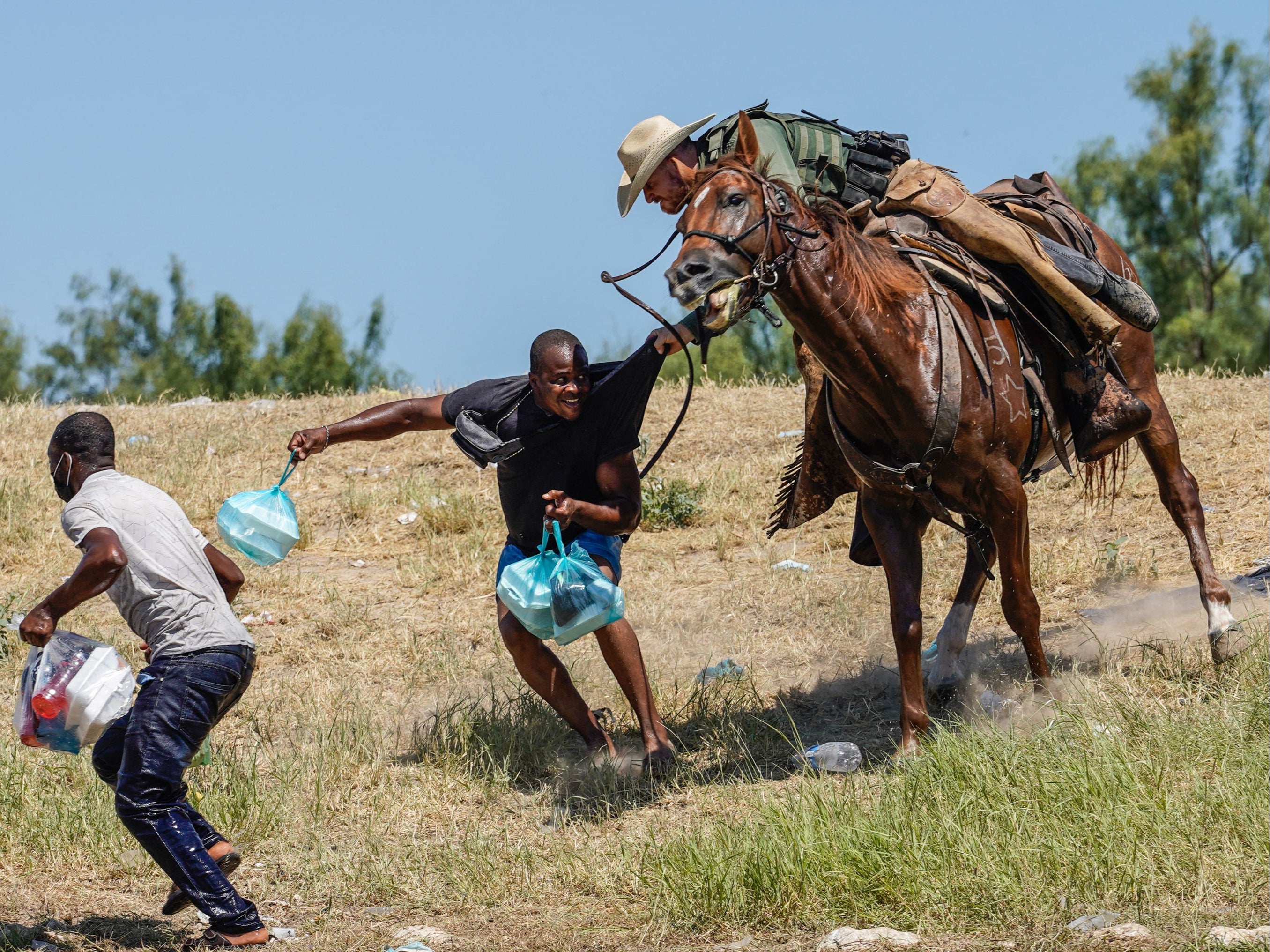 An agent for US Border Patrol tries to stop a migrant entering the US