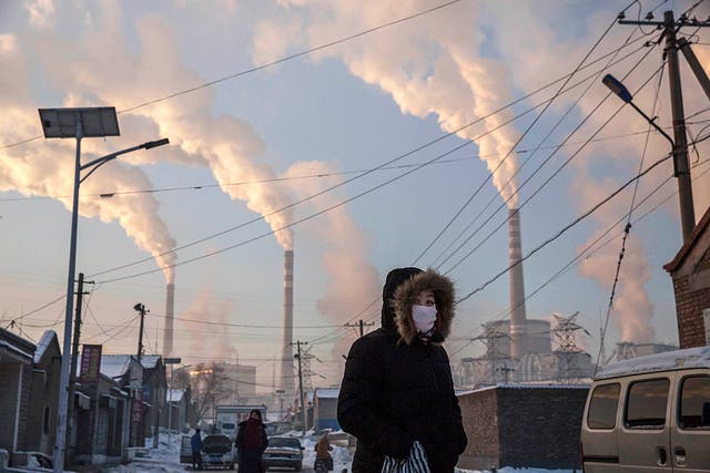 <p>Smoke billows from stacks as a woman wears as mask while walking near a coal-fired power plant in Shanxi, China. President Xi Jingping announced at the UN General Assembly this week that China would stop building coal plants overseas</p>