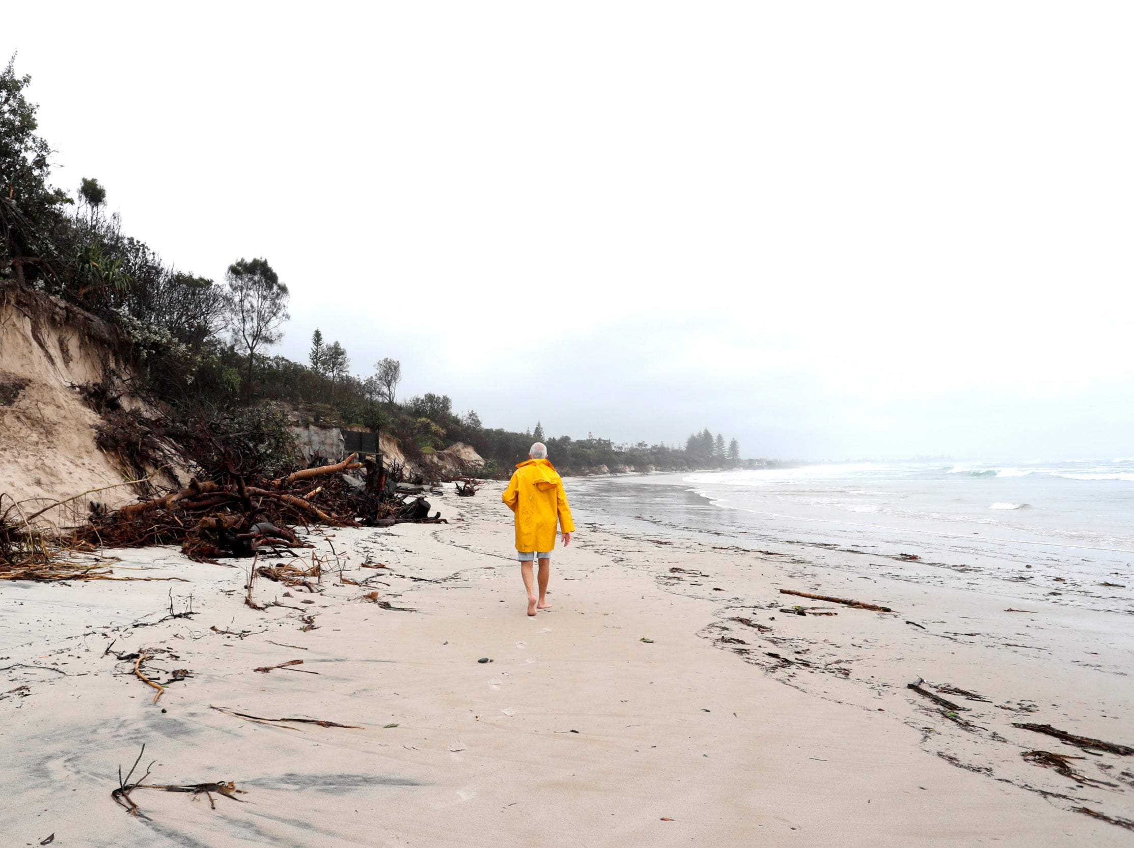 <p>A man walking along a stretch of coast in Byron Bay</p>