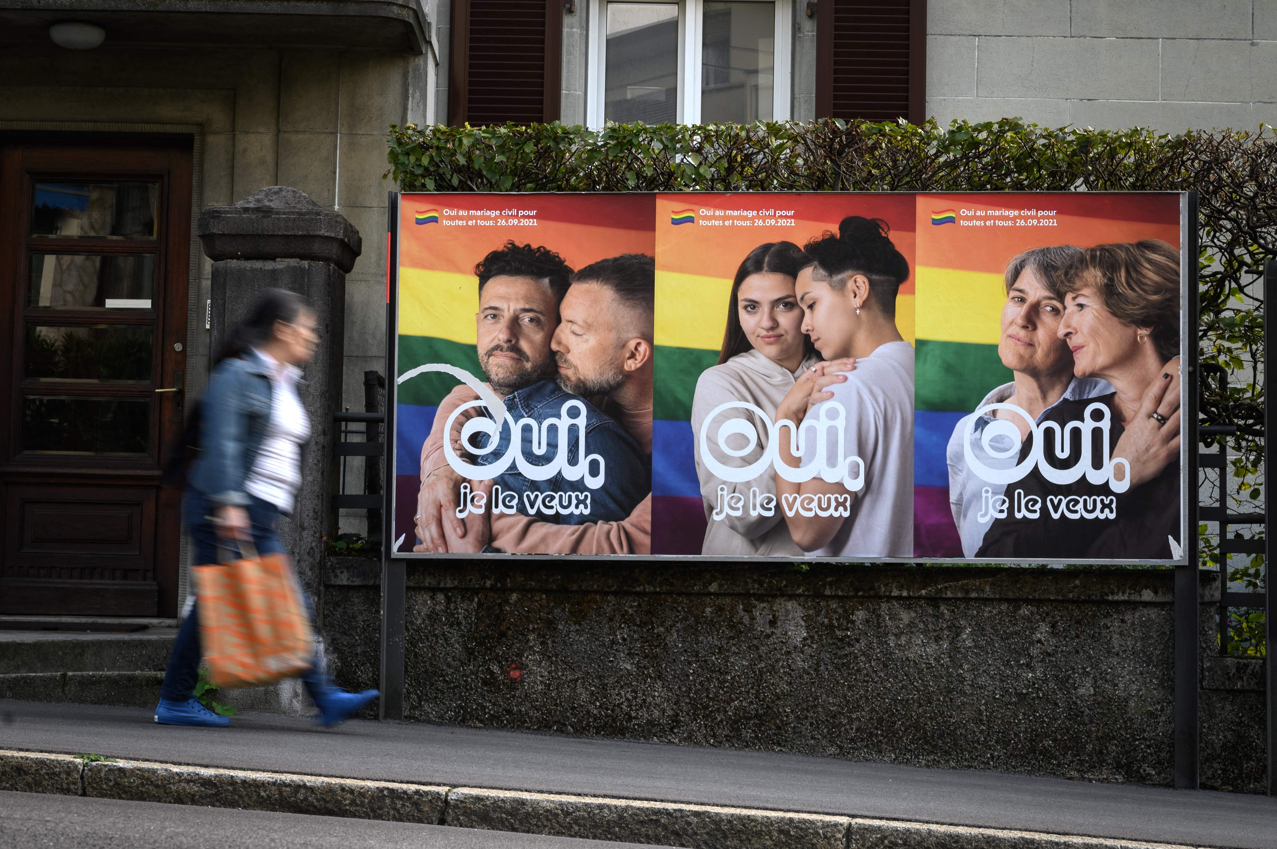 A woman walks past an electoral poster in the town of Lausanne, Switzerland ahead of a nationwide vote on same-sex marriage