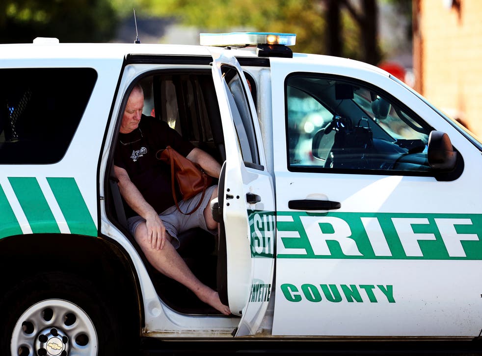 <p>A man sits in Sheriff’s vehicle following the shooting </p>