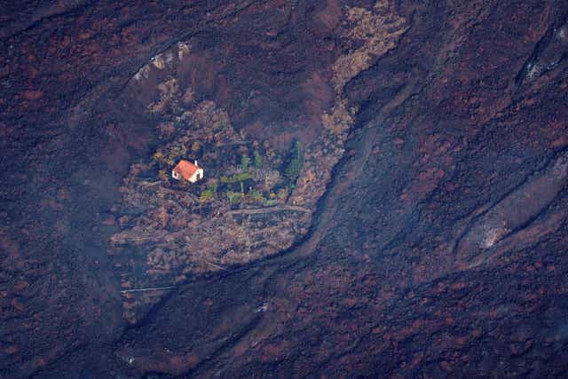 <p>A dramatic image shows lava surrounding a house following the eruption of a volcano in the Cumbre Vieja national park at El Paso, on the Canary Island of La Palma</p>