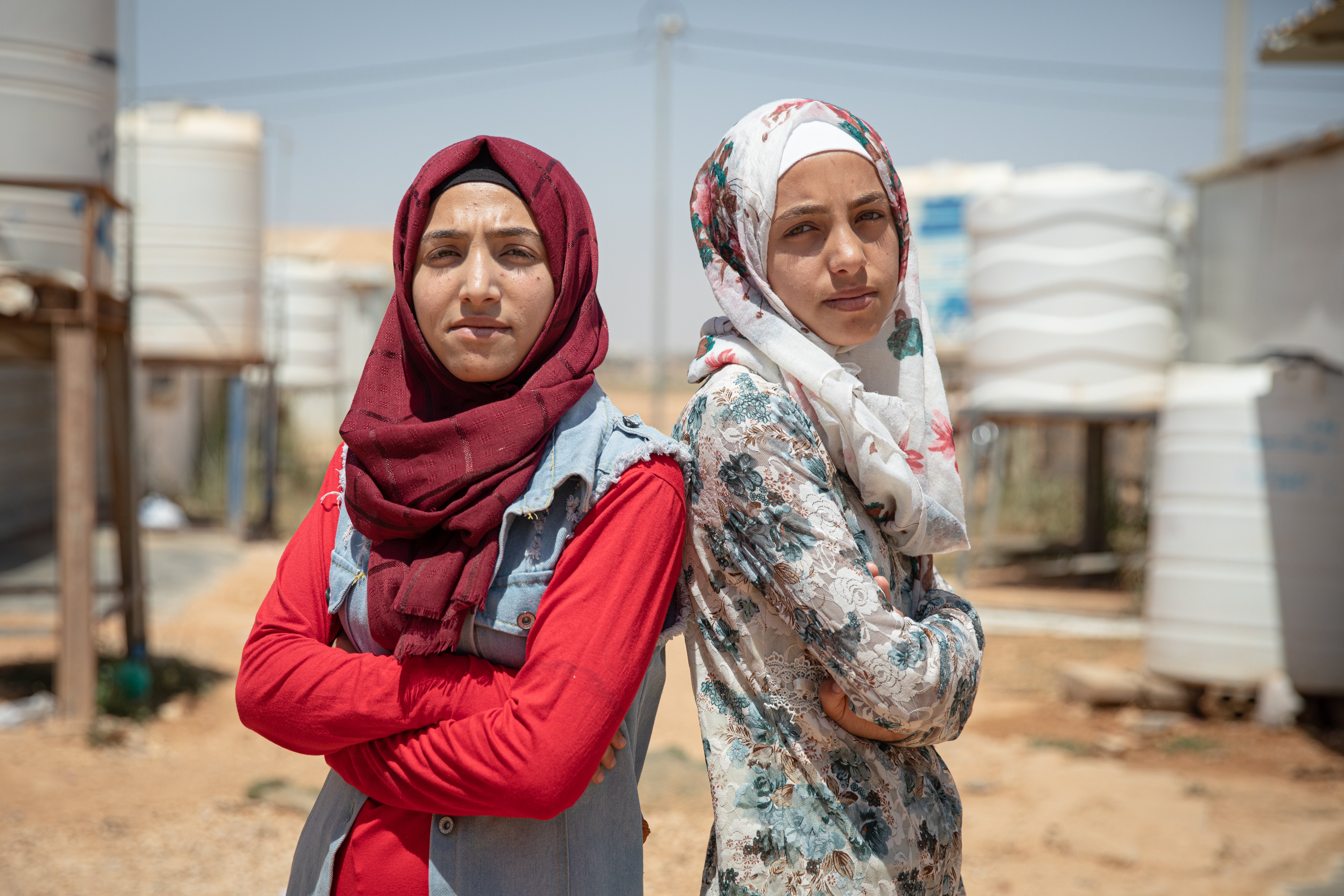 Hiba* (red shirt), 17, and Rama*, 14, outside their family caravan in Za’atari camp for Syrian refugees, Jordan. The Syrian sisters are using rap music to spread a crucial message about girls’ rights