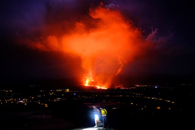<p>Two people walk as lava spews from a volcano on the Canary island of La Palma in the early hours of Saturday </p>