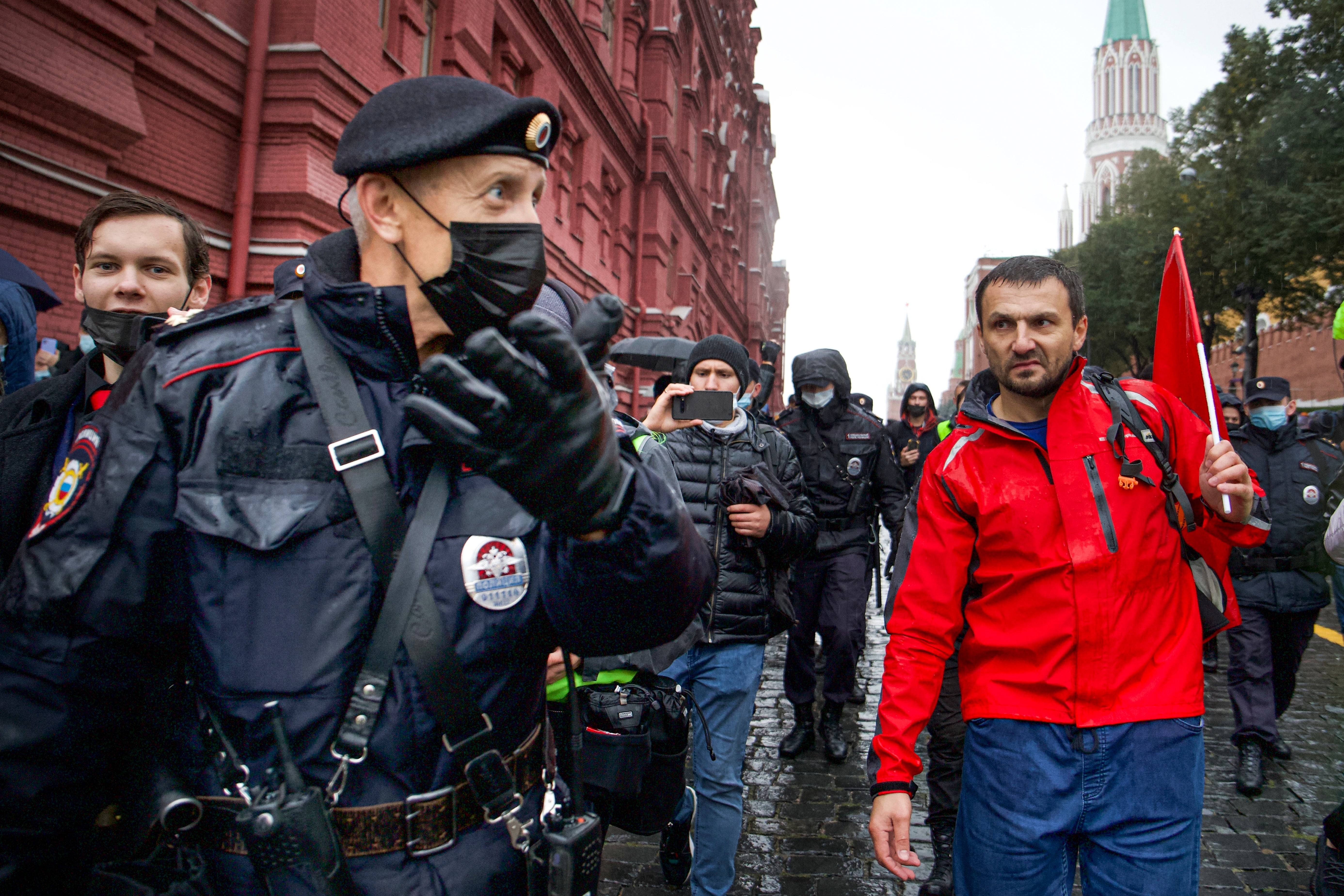 Police escort a demonstrator near Red Square in Moscow during Saturday’s muted protest against election fraud